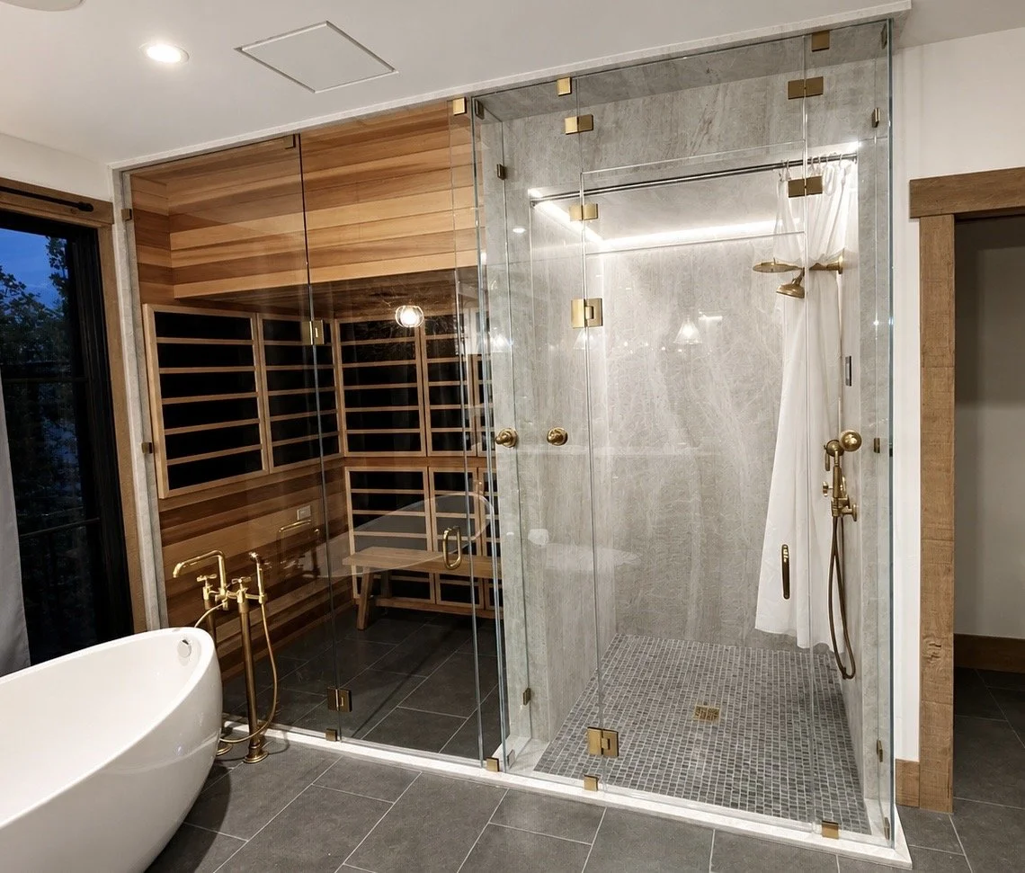 Modern bathroom with a glass-enclosed shower, a freestanding bathtub, wooden accents, and a cedar sauna at the back.
