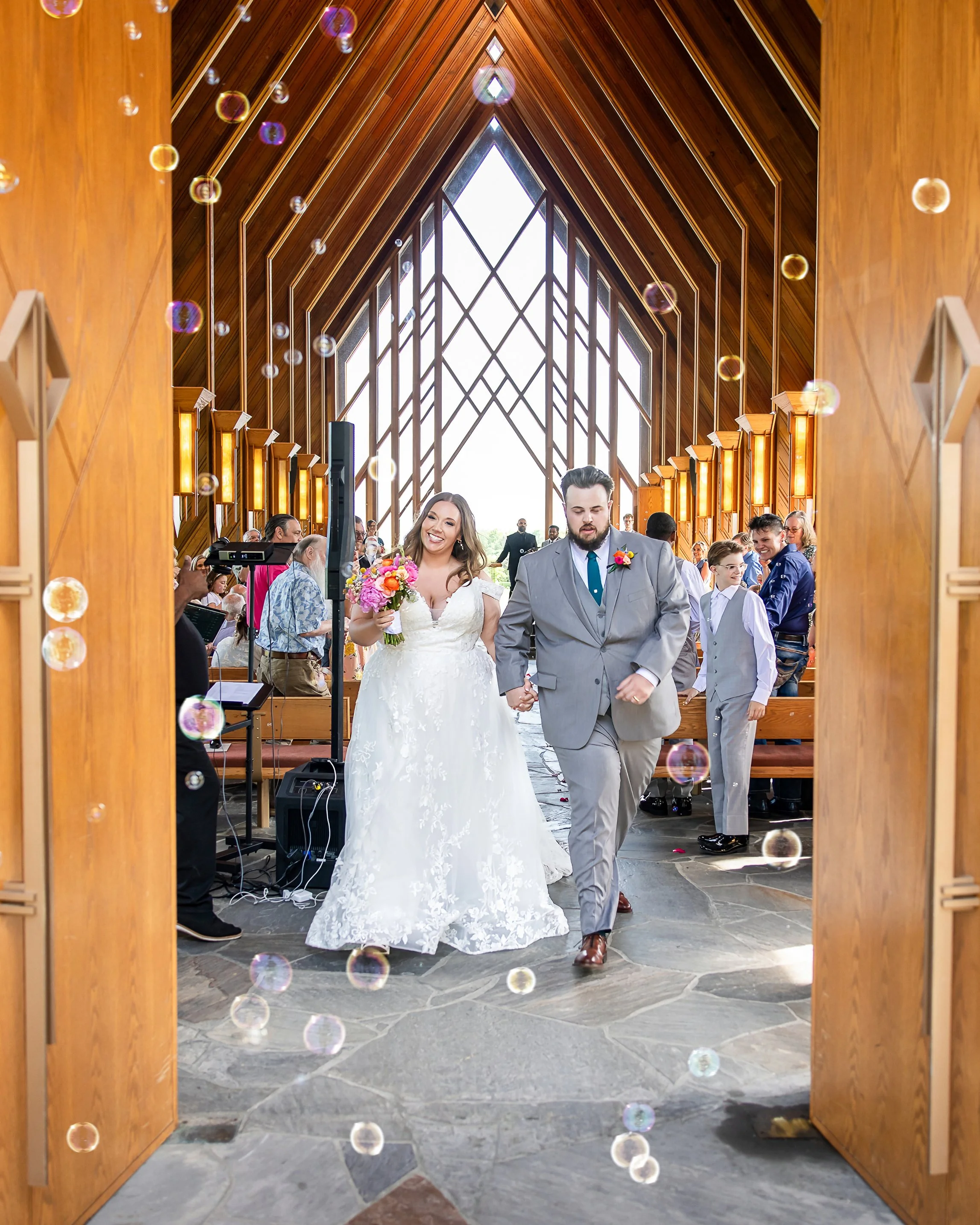 Bride and Groom walking through bubbles as the exit the Powell Gardens Chapel