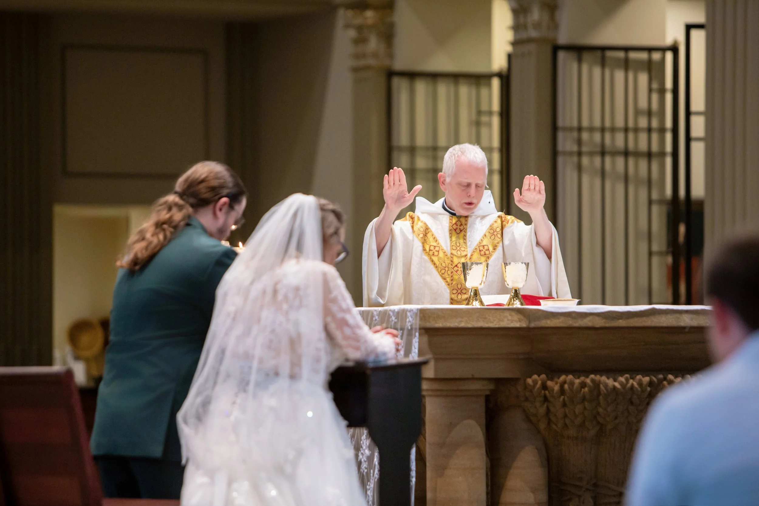A priest conducting a religious ceremony at an altar during a church service, with congregants praying.