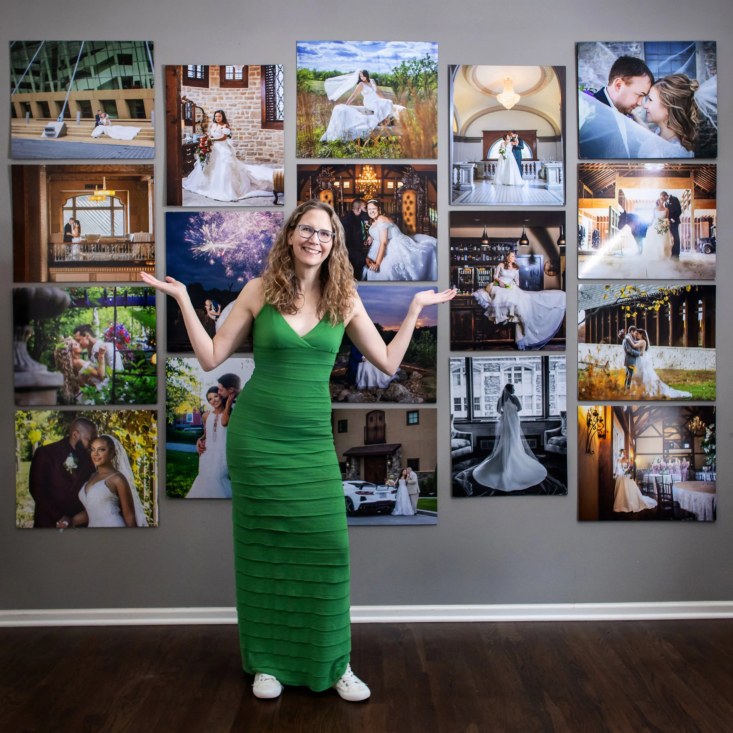 Your Kansas City Wedding Photographer, Angi.  Angi is dressed in green, standing in front of a wall full of hanging wedding portraits of various couples.