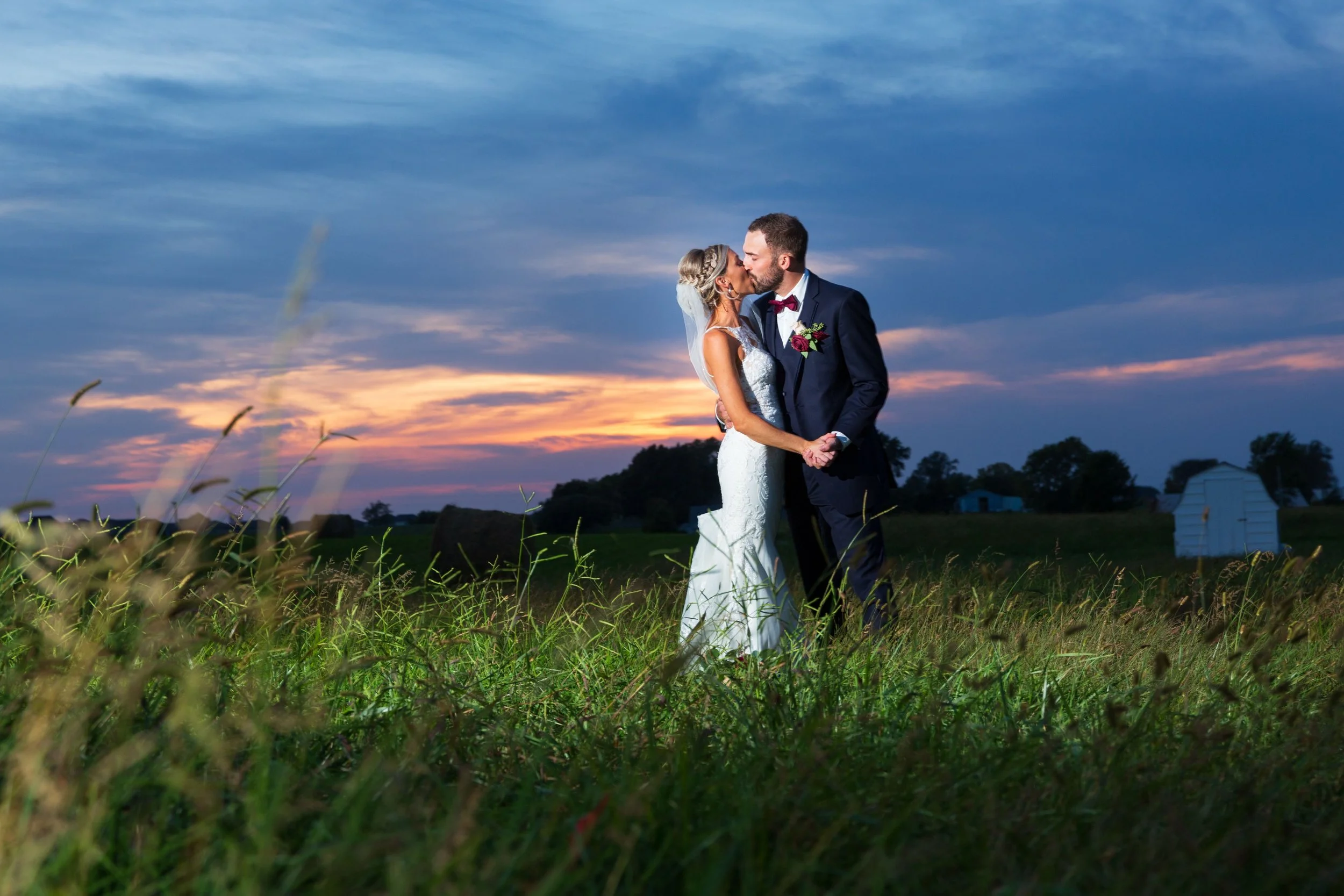 Wedding Photographer photographs Bride and Groom in front of a sunset at the venue Lone Summit Ranch.