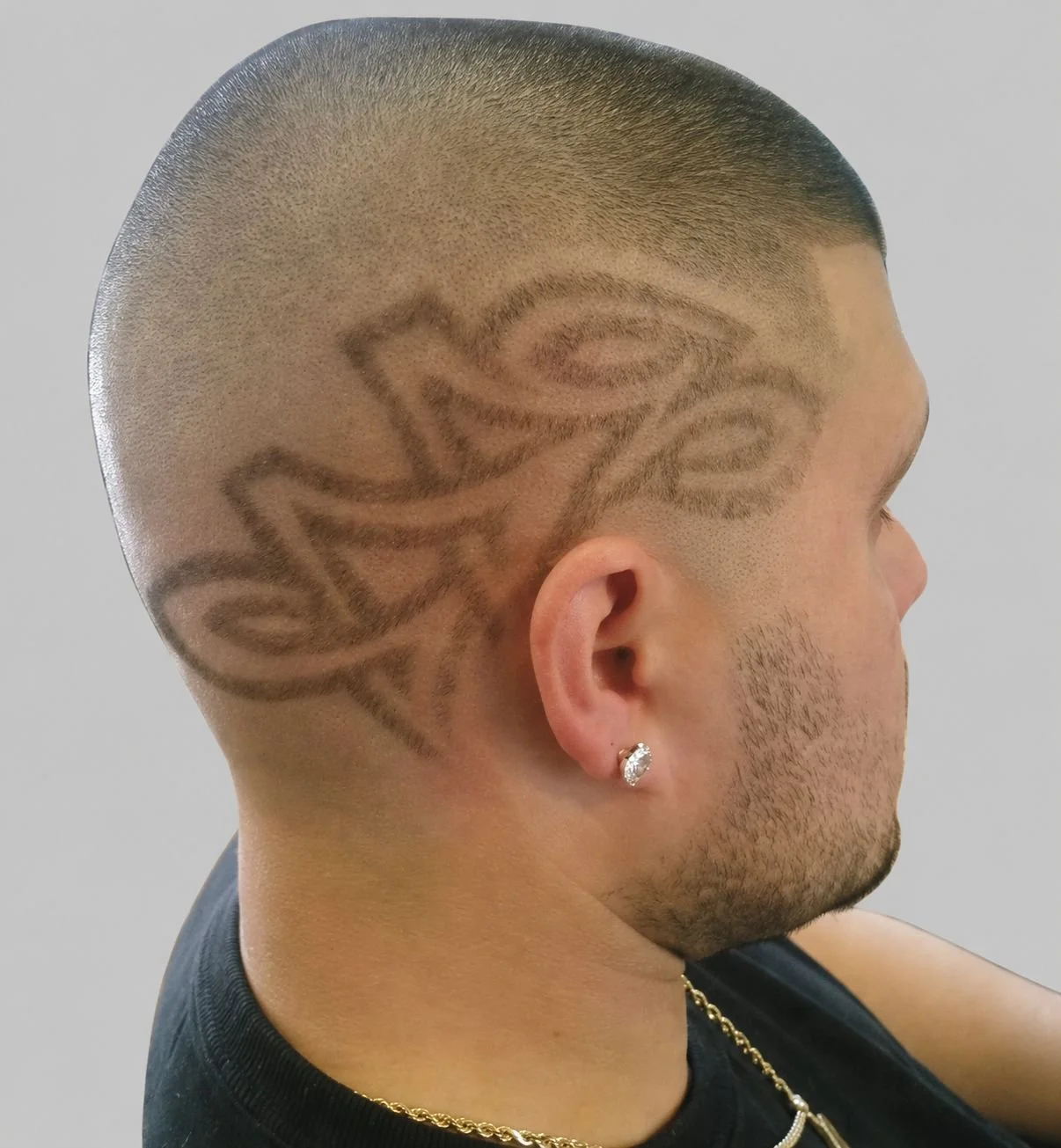 Side profile of a man with a shaved head featuring a tattoo of the words 'Love You' in stylized cursive writing.