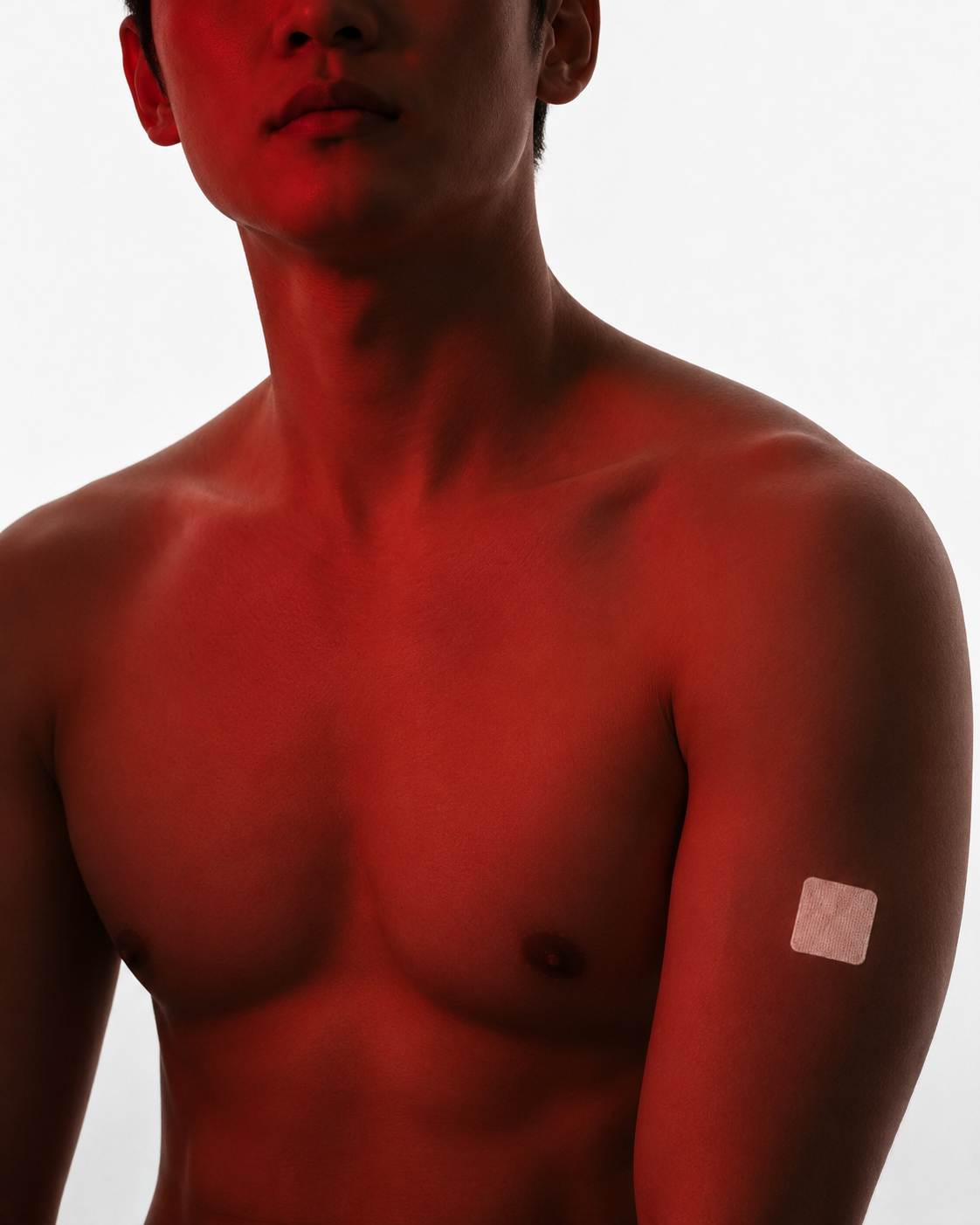 Close-up of a shirtless person with red paint on their shoulder, collarbone, and neck, and a small bandage on their upper arm.