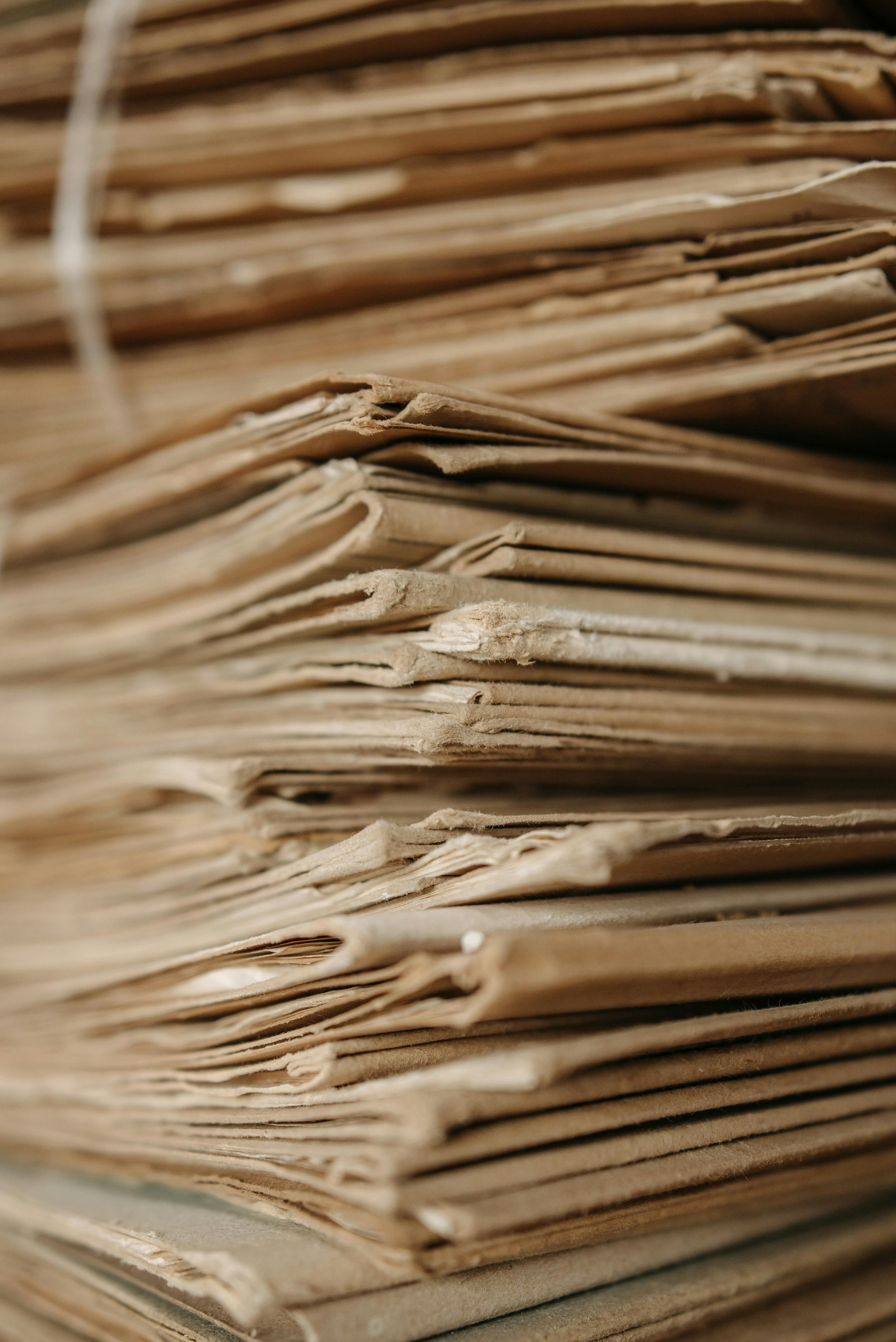 Close-up of stacked old paper files or documents, showing the rough, worn edges of the pages.