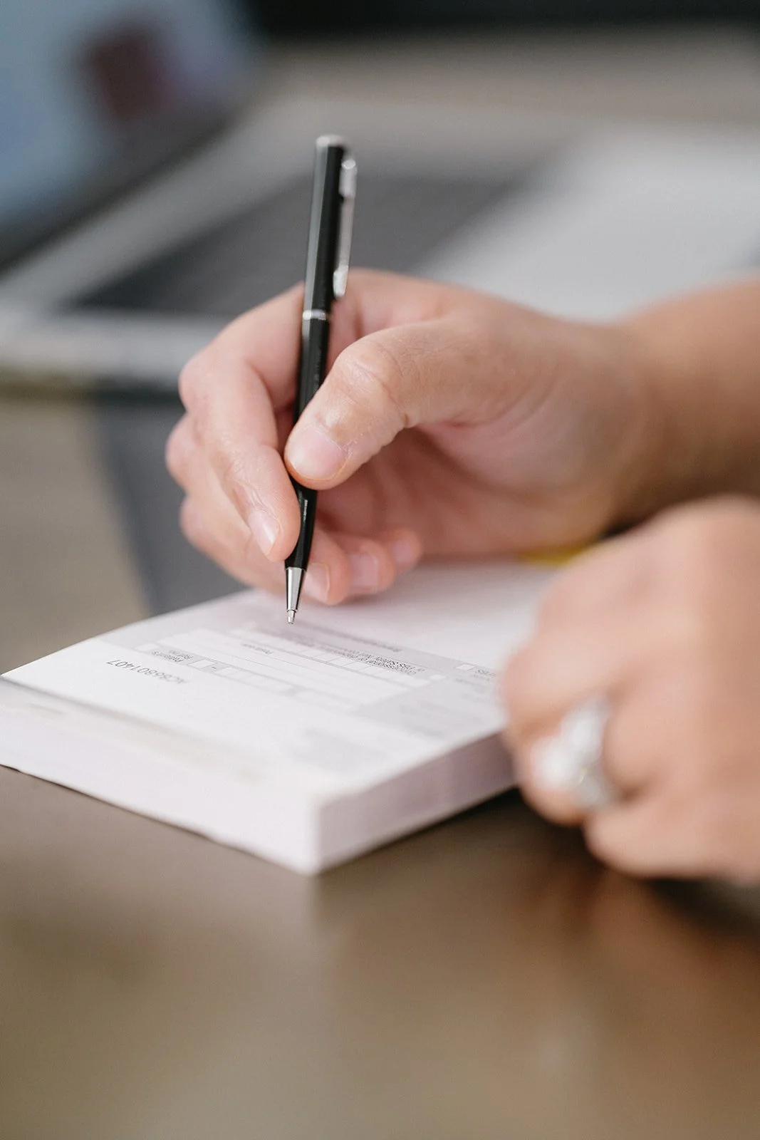 Person signing a check with a black pen.