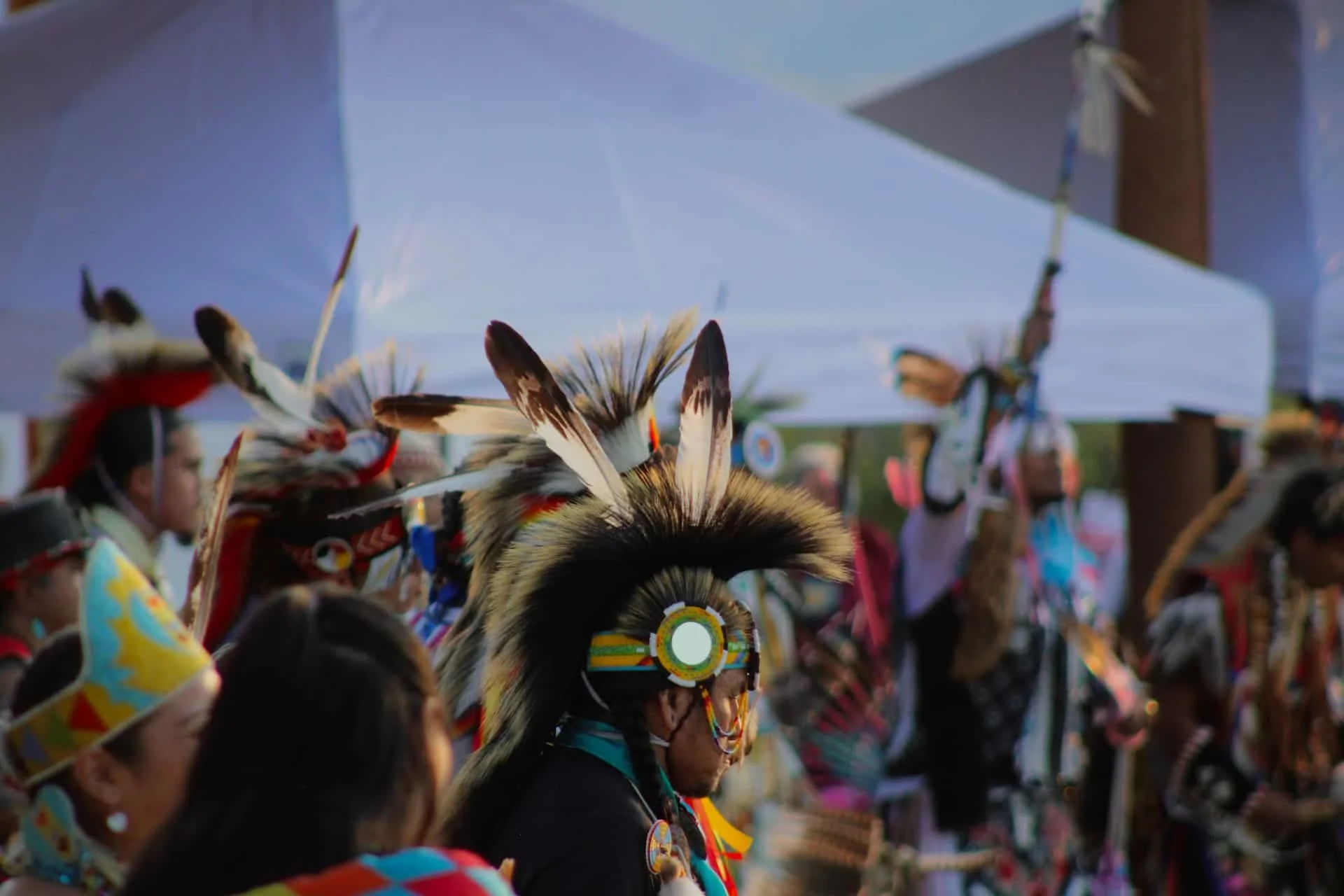 Native American dancers wearing traditional feathered headdresses and colorful clothing at a cultural event.