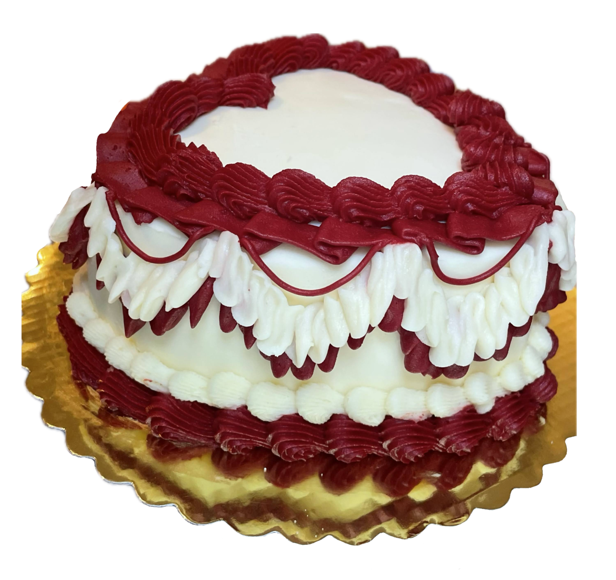 A round cake with white frosting, decorated with red piped icing and red fondant strips on top, resting on a gold-colored cake board.