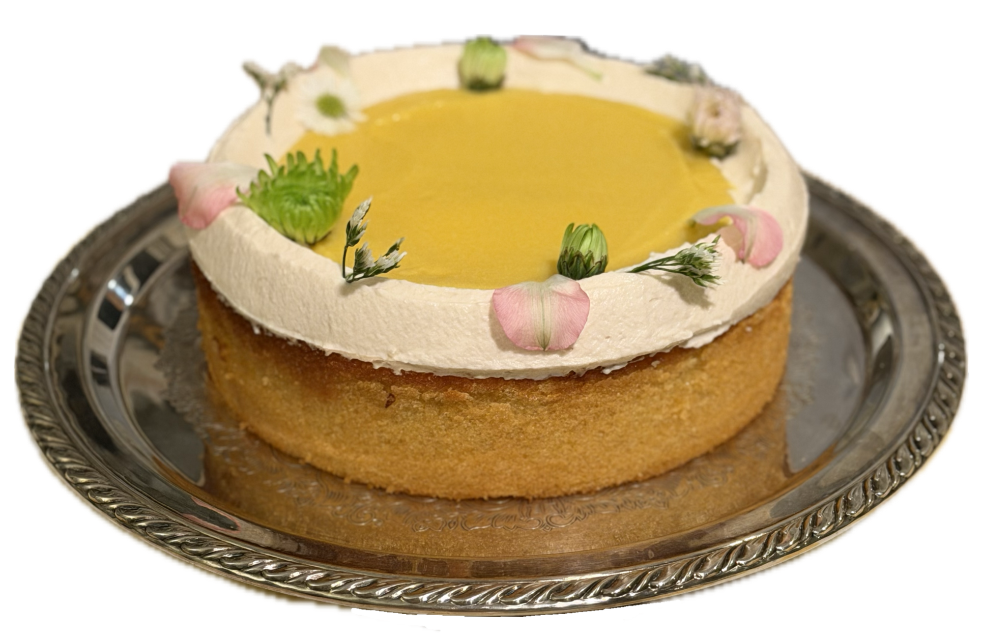 A round cake with yellow filling and white frosting, decorated with pink and white flower petals, green leaves, and placed on a silver platter with ornate edges.