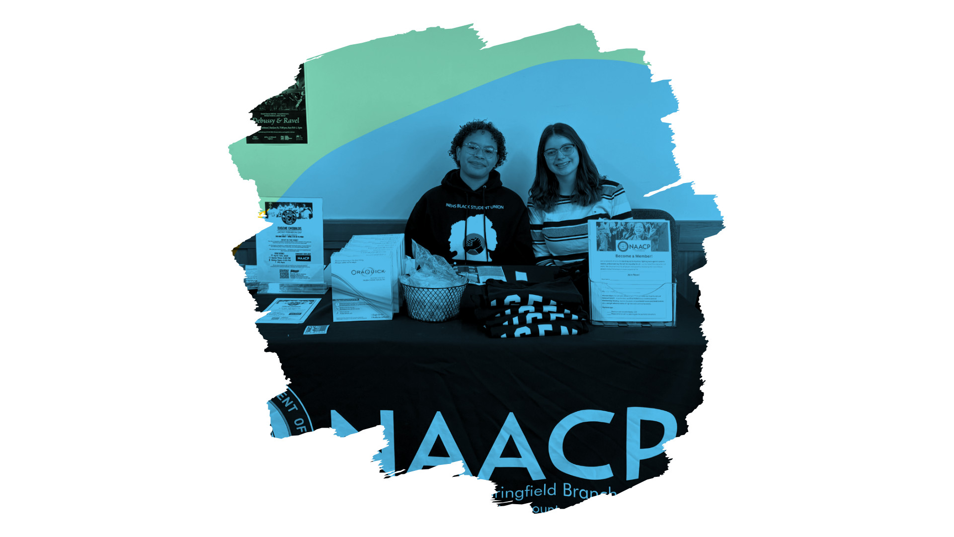 Two people sitting behind a table with NAACP flyers and materials, promoting membership and support for the NAACP Eugene-Springfield, Oregon