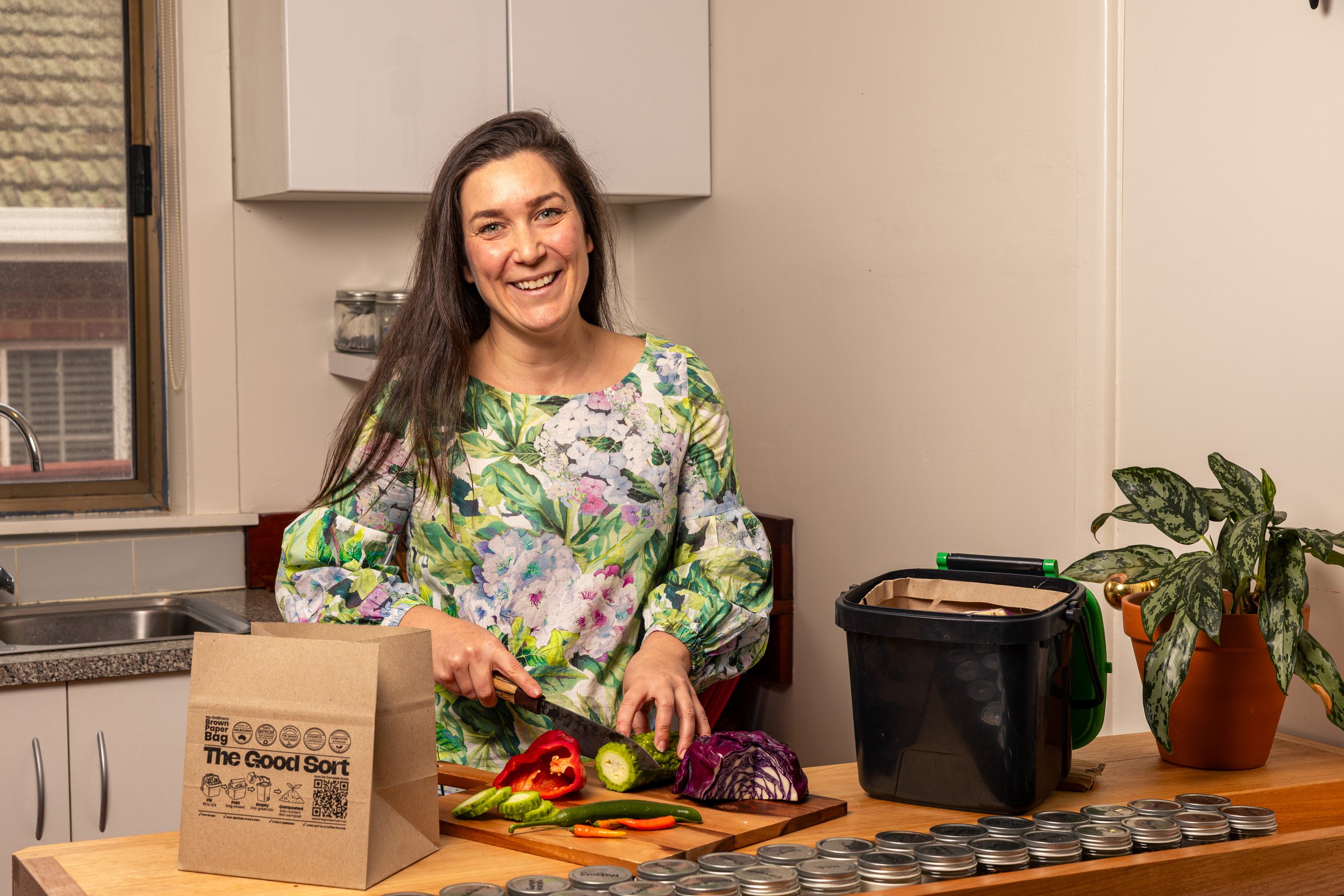 The Good Sort - Person preparing vegetables beside The Good Sort paper caddy liners and kitchen food waste caddy.