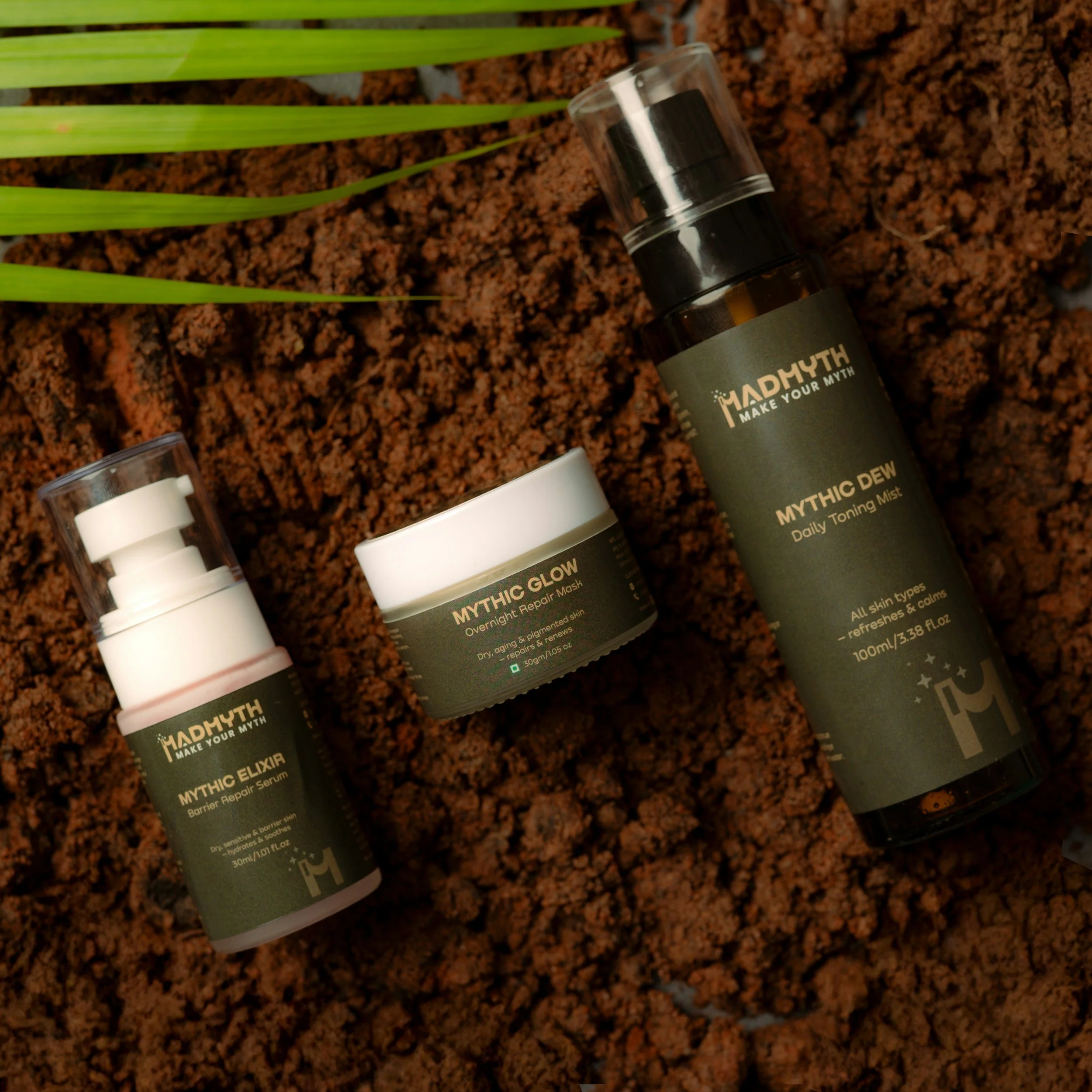Close-up of skincare product bottles on a textured surface with green leaves.