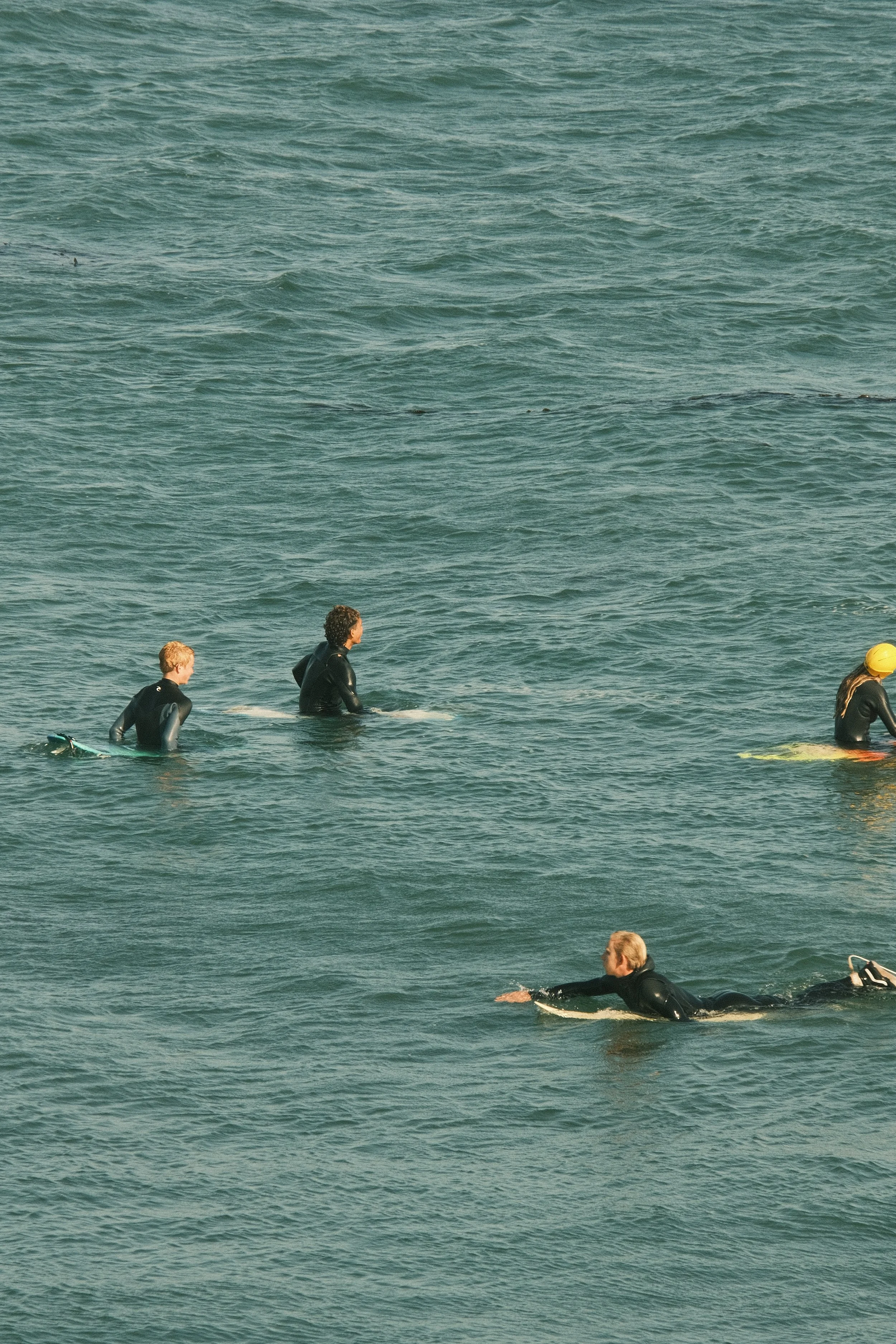 People surfing in the ocean, some paddling on surfboards and others riding on their boards.