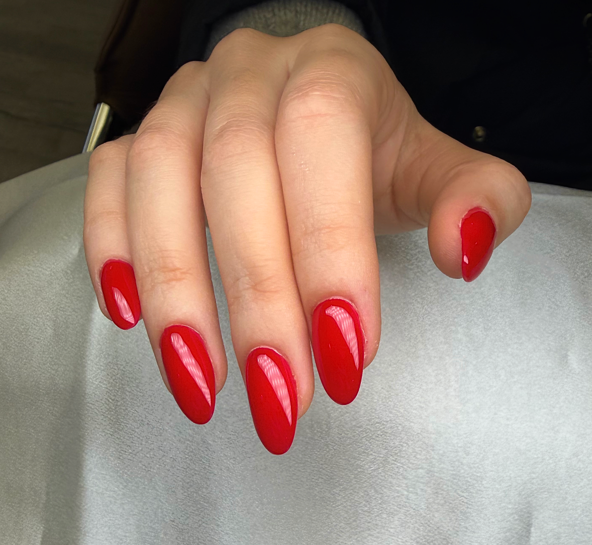 Close-up of a person's hand with red painted nails resting on a light surface.