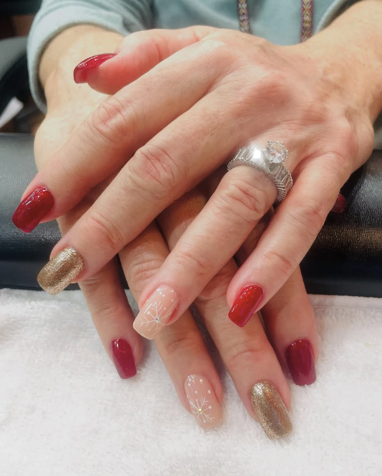 Close-up of hands with red, nude and gold decorated nails.