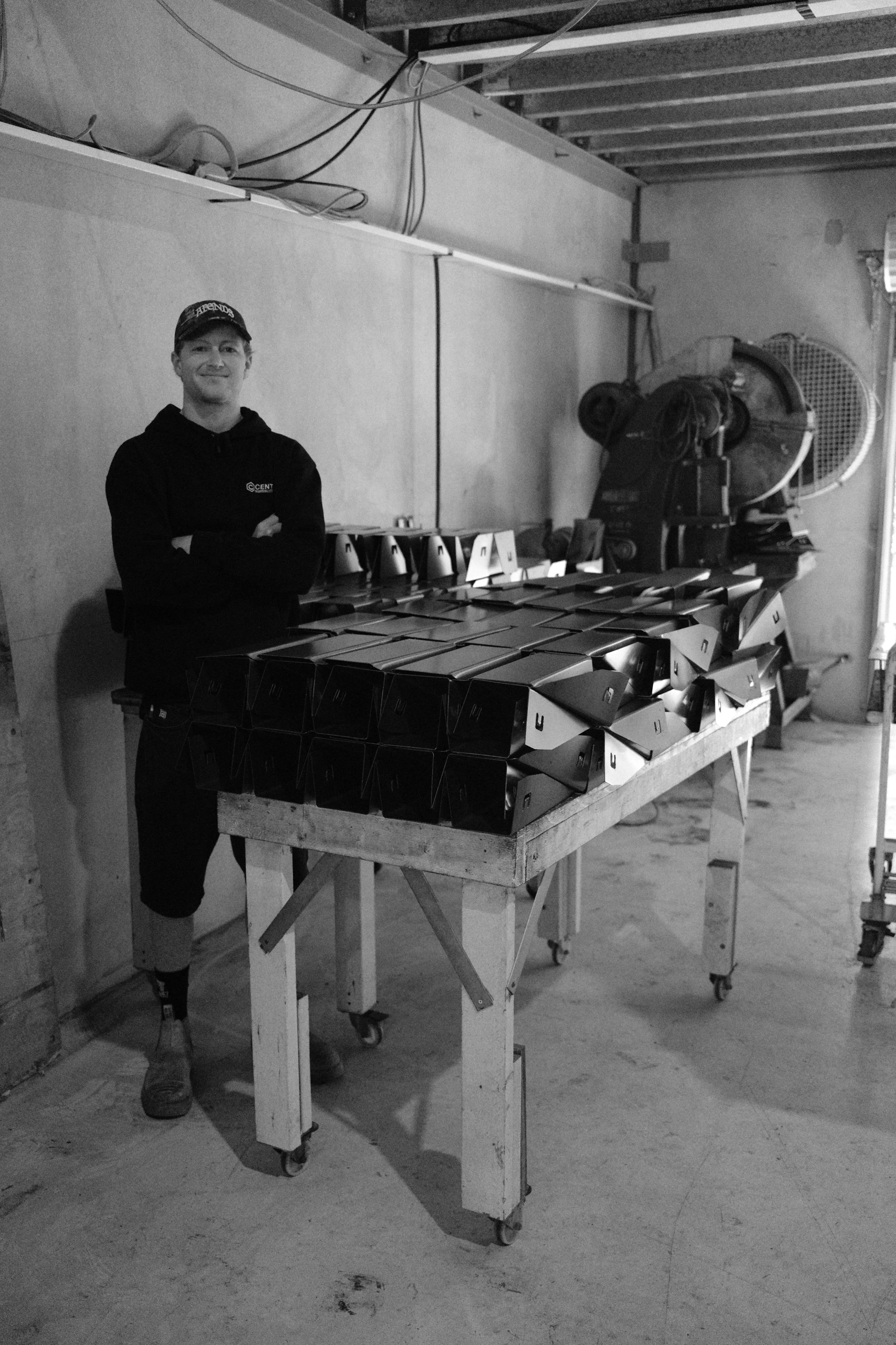 A person standing with arms crossed in front of a table full of AdaptaKerbs ready to be welded.