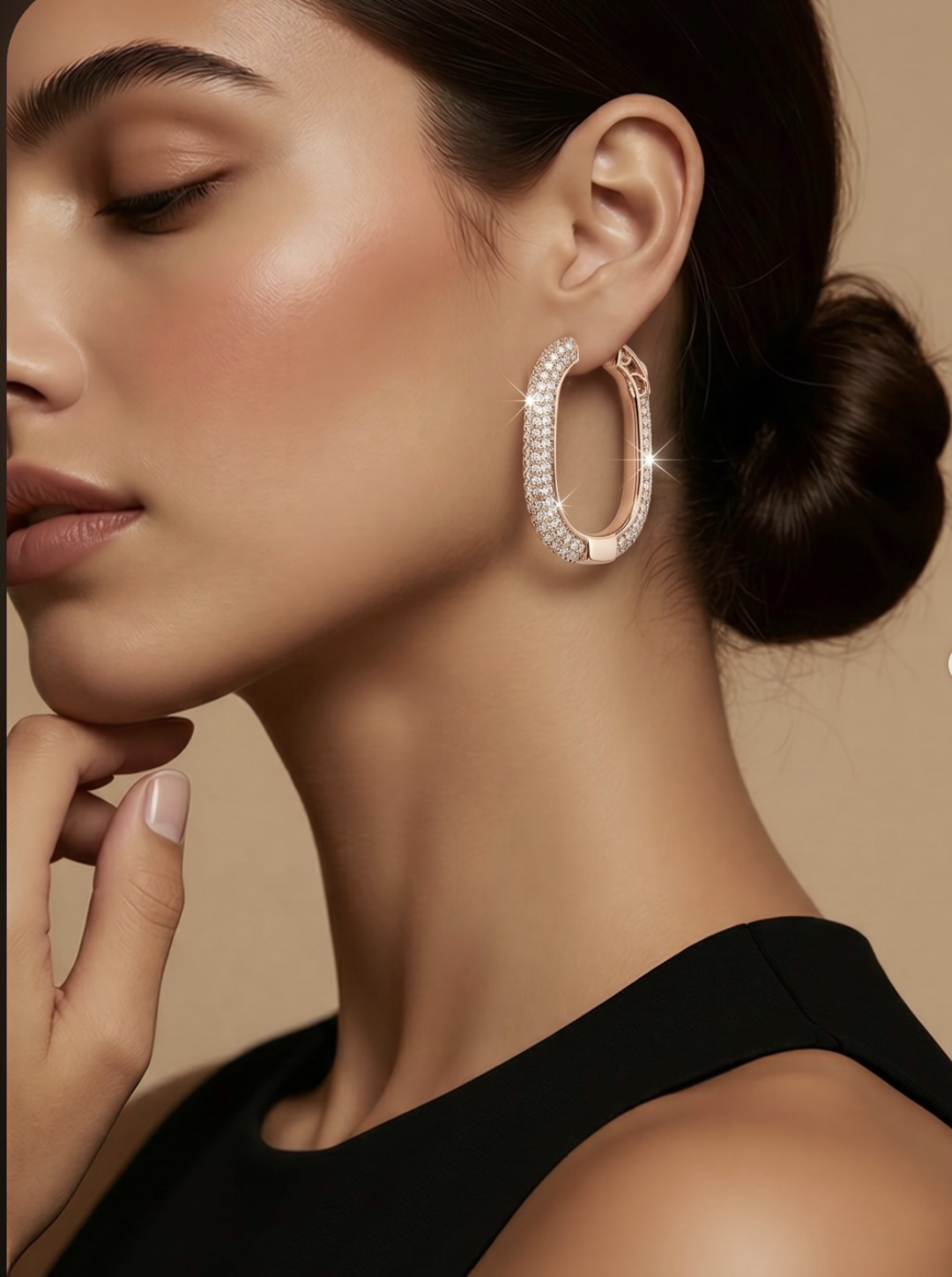 A close-up of a woman with elegant jewelry, wearing a large, diamond-encrusted hoop earring, with her eyes closed and hand touching her cheek.