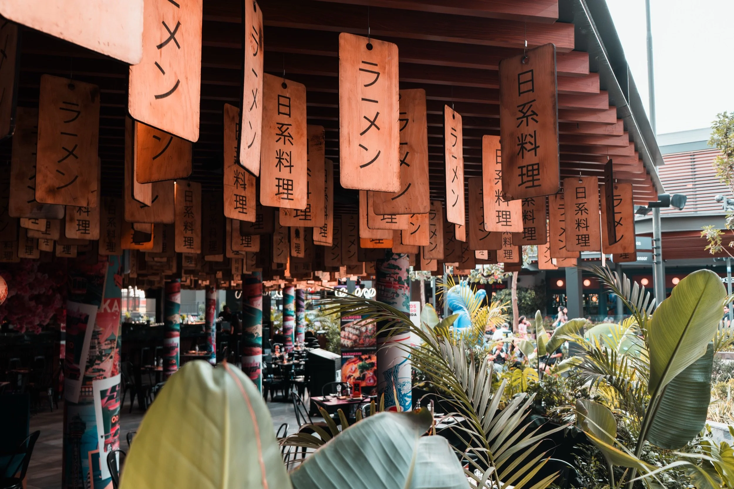 Letreros de un restaurante japonés de ramen entre plantas
