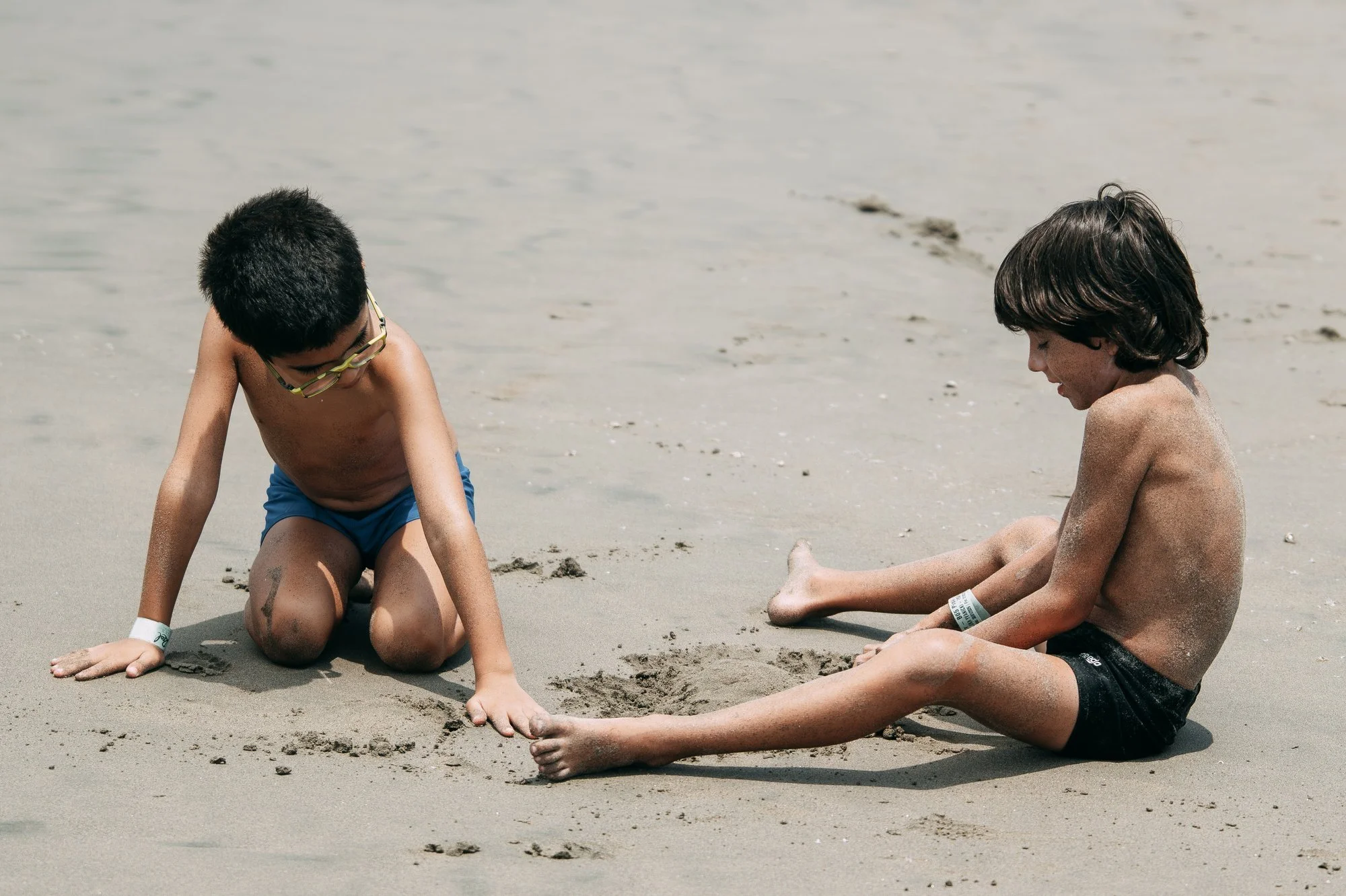 Dos niños jugando con la arena en la playa