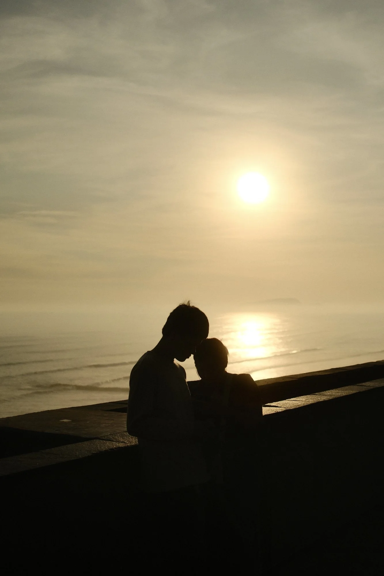 Silueta de una pareja abrazada frente al mar al atardecer