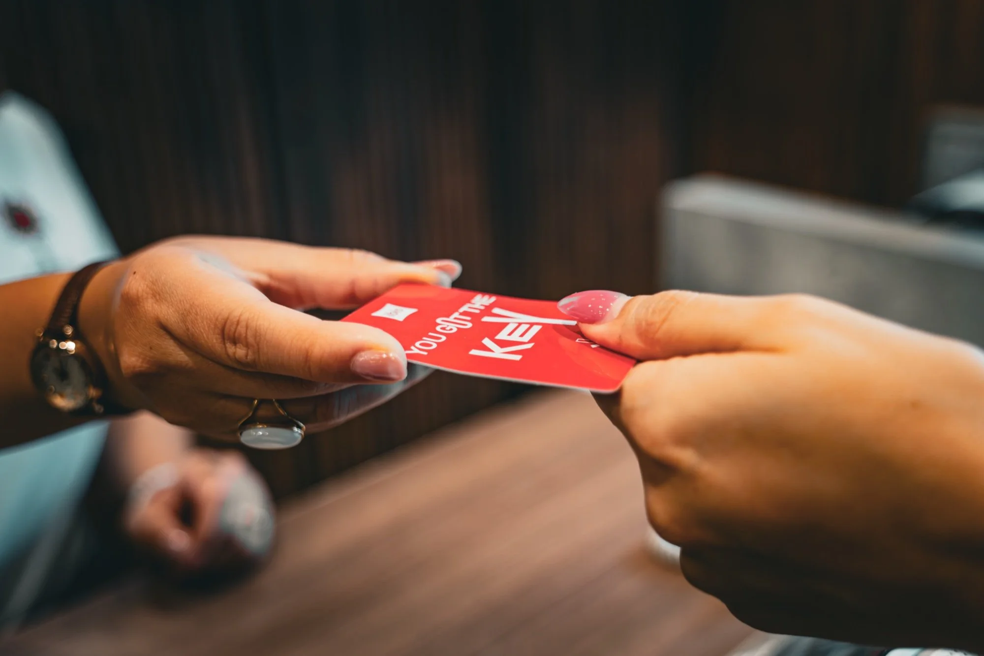 Manos intercambiando una tarjeta-llave roja del hotel