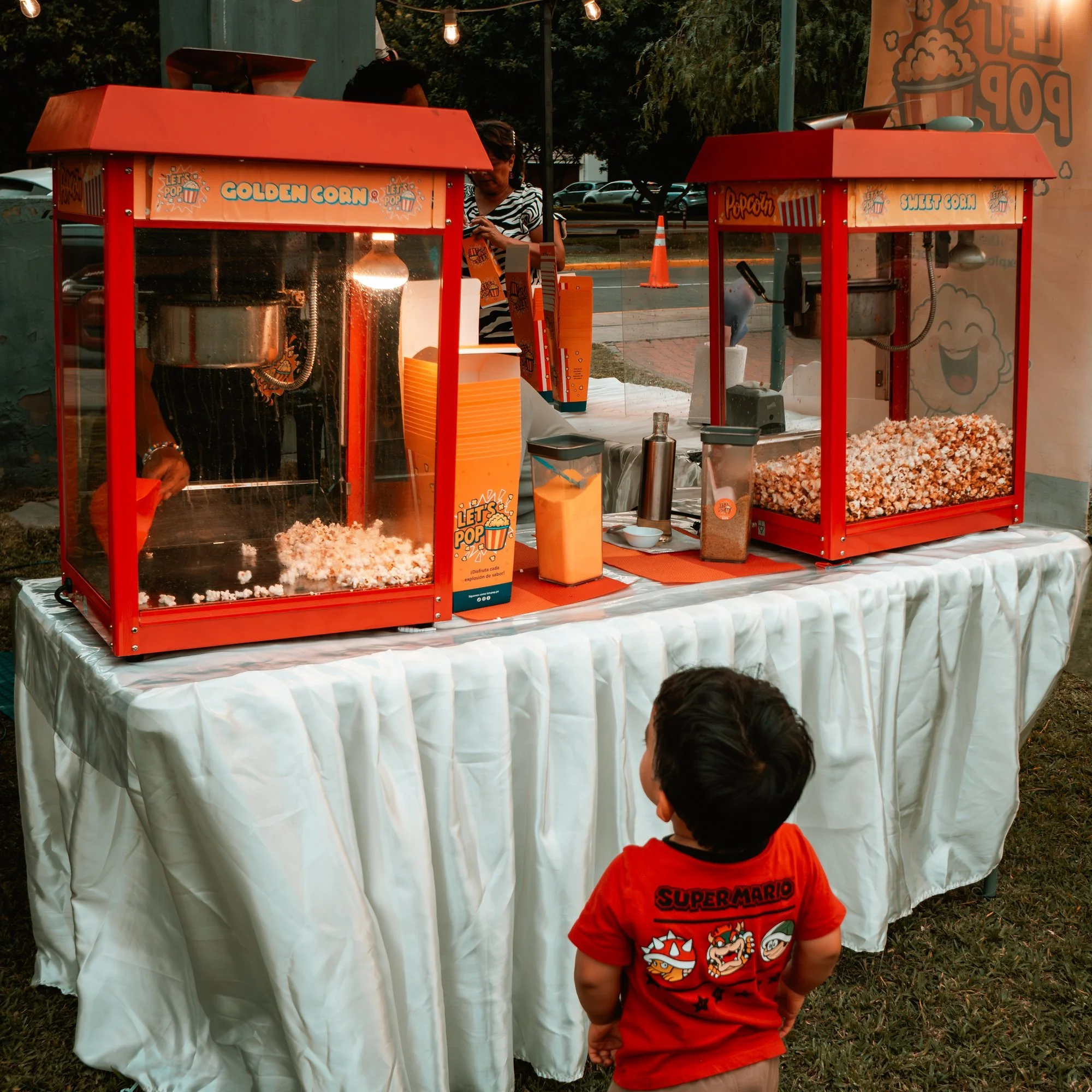 Niño frente a un puesto de canchita en la feria