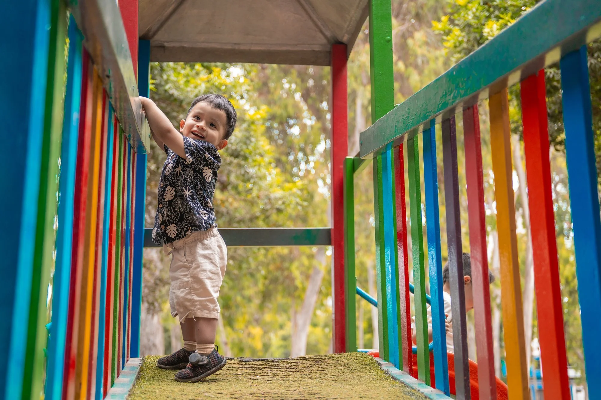 Niño asomado a un tobogán de tubos de colores