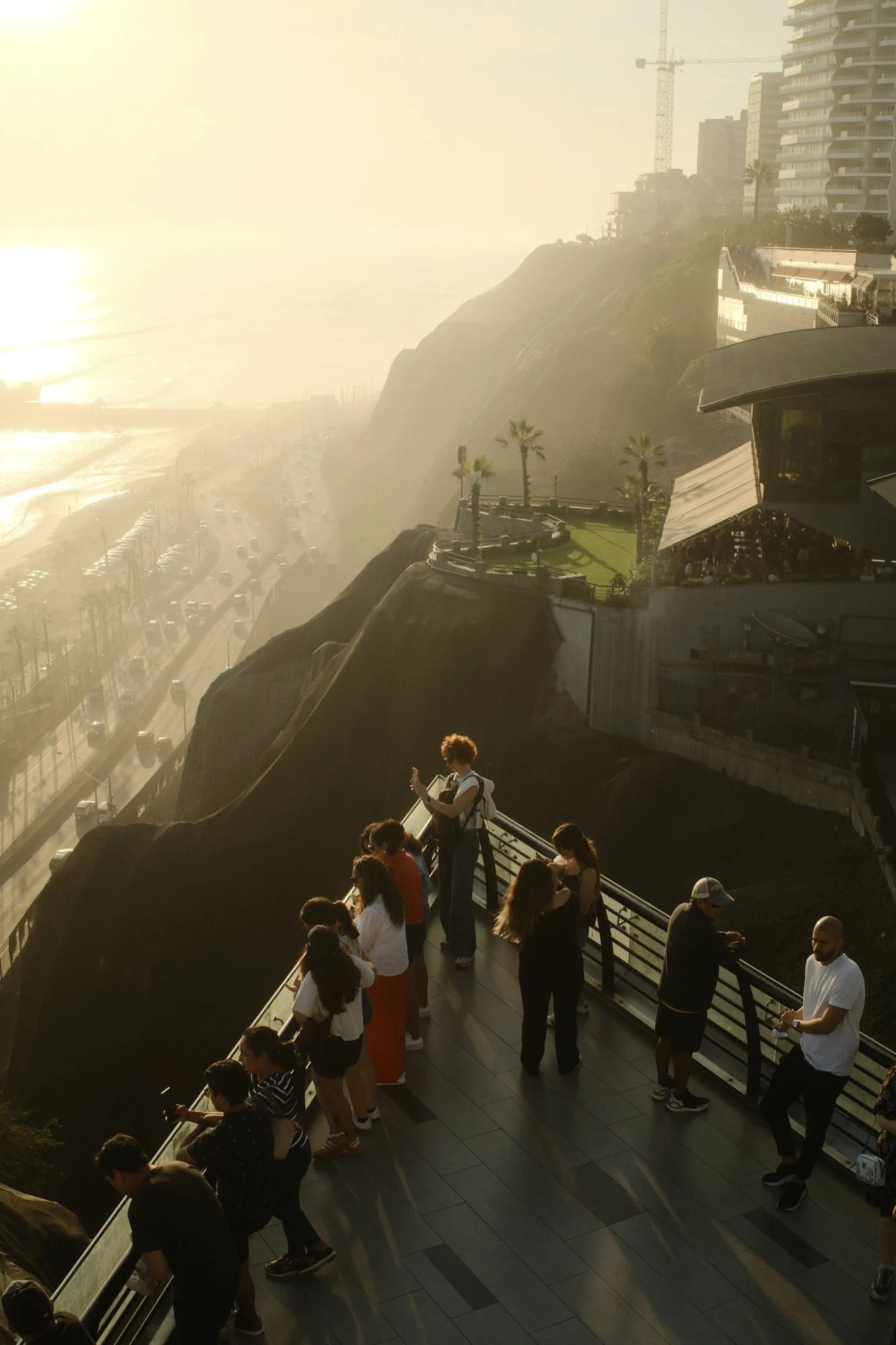 Gente reunida en un mirador observando la costa neblinosa de Lima