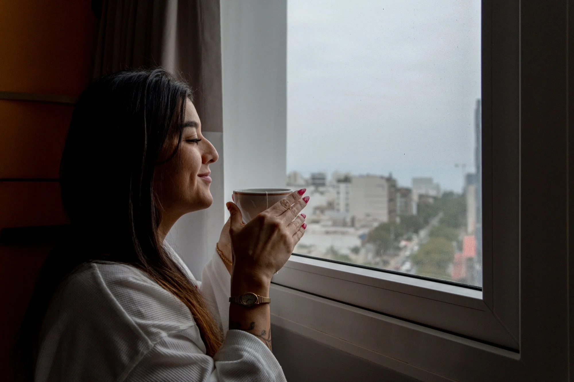 Huésped tomando café junto a la ventana de la habitación