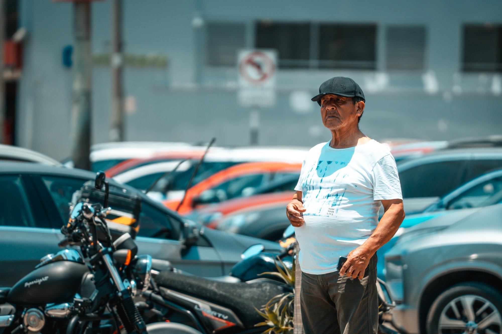 Hombre con gorra entre motos y autos en un estacionamiento