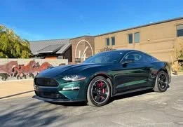 Black sports car parked outdoors in front of a beige building under a blue sky.