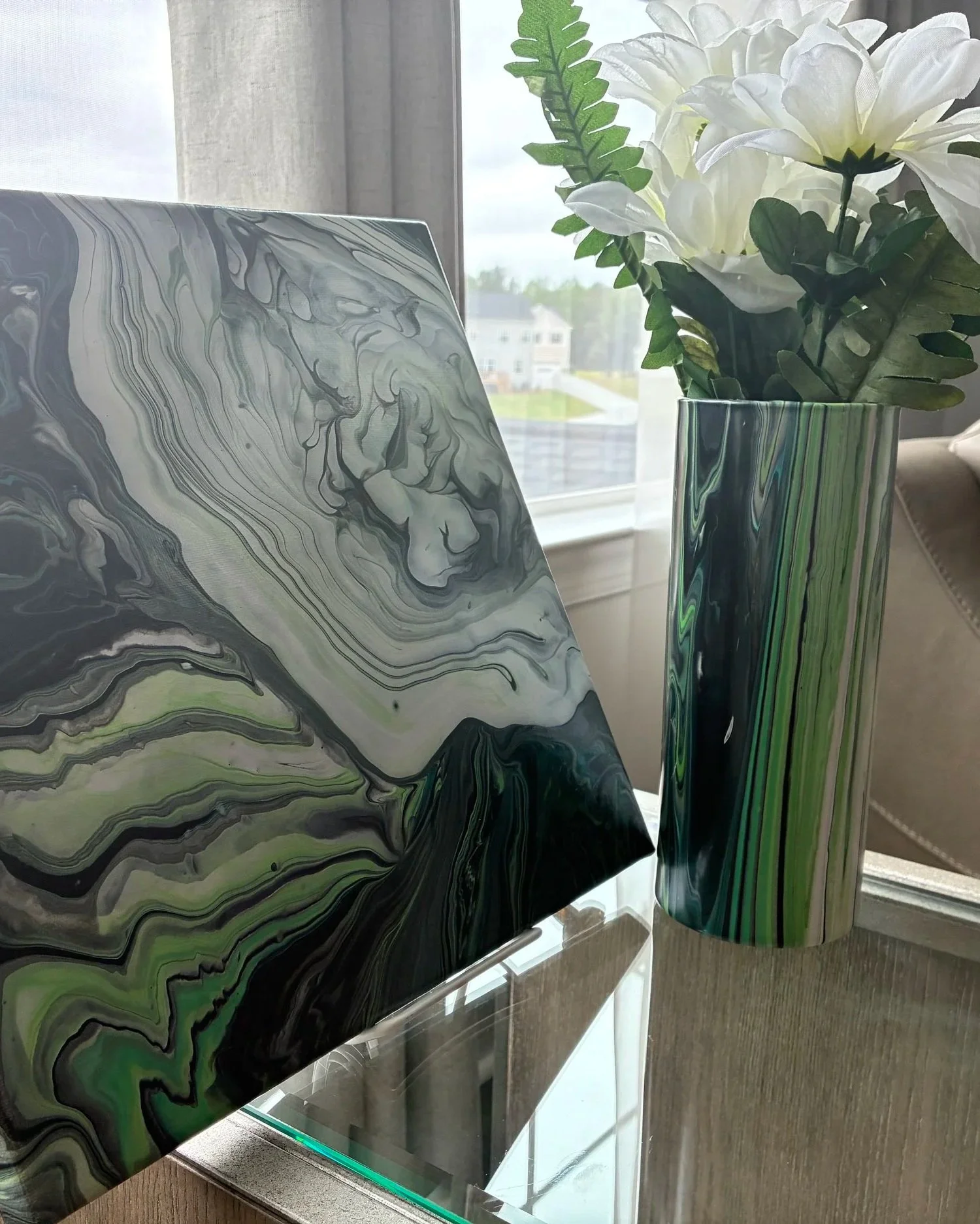 Modern acrylic pour canvas and decorative vase pairing featuring layered emerald, ivory, and charcoal movement inspired by natural stone and flowing mineral textures.