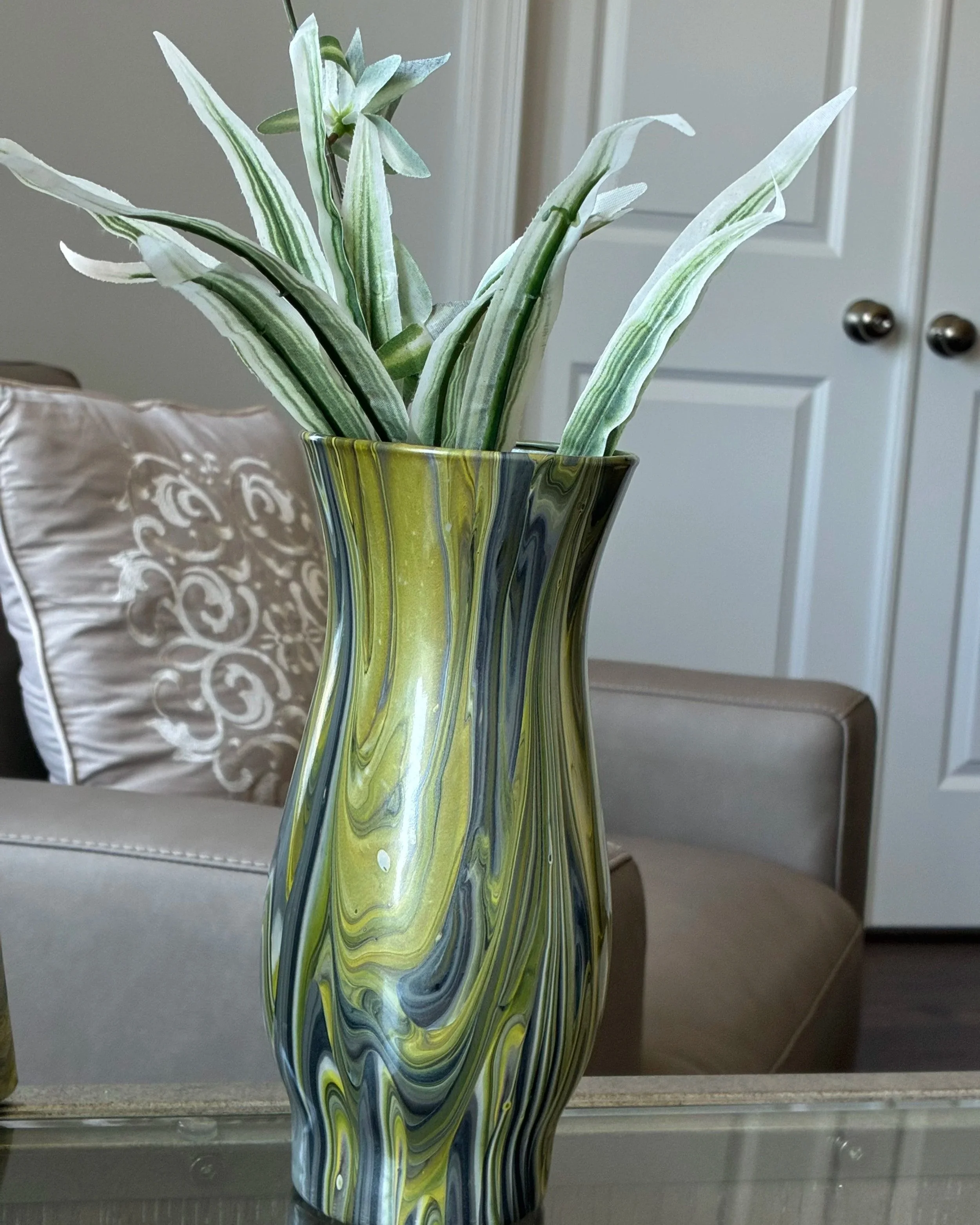 Flowing ribbons of emerald, moss, and shadowed metallic tones wrap the vessel in graceful movement, capturing the vitality of nature and the quiet glow of renewal.