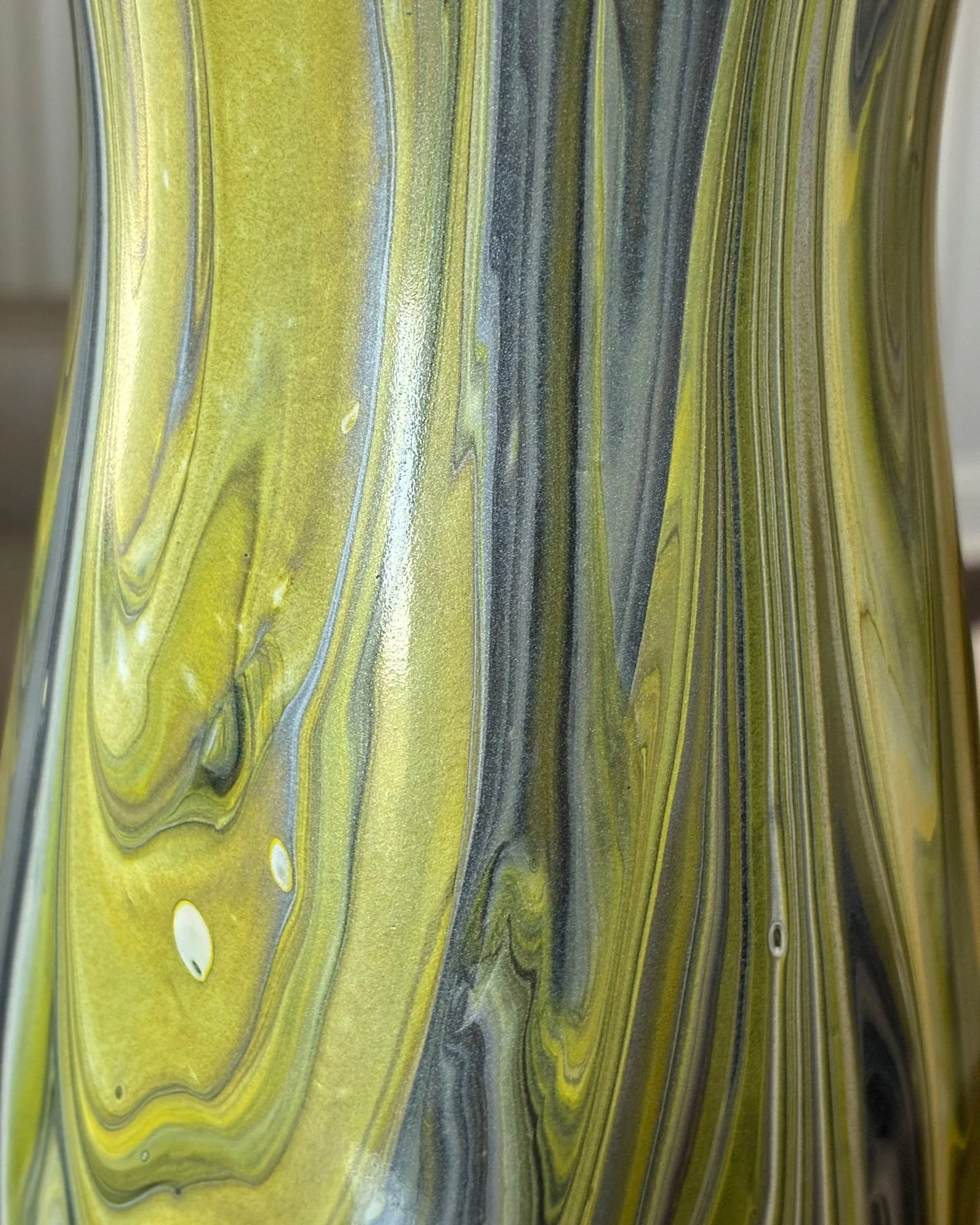 Flowing layers of moss green, olive, charcoal, and metallic tones reveal the movement and depth at the heart of Verdant Flame