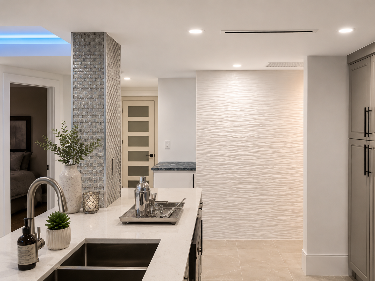 Modern kitchen with white countertops, grey cabinets, textured wall, decorative plants, and stainless steel appliances.