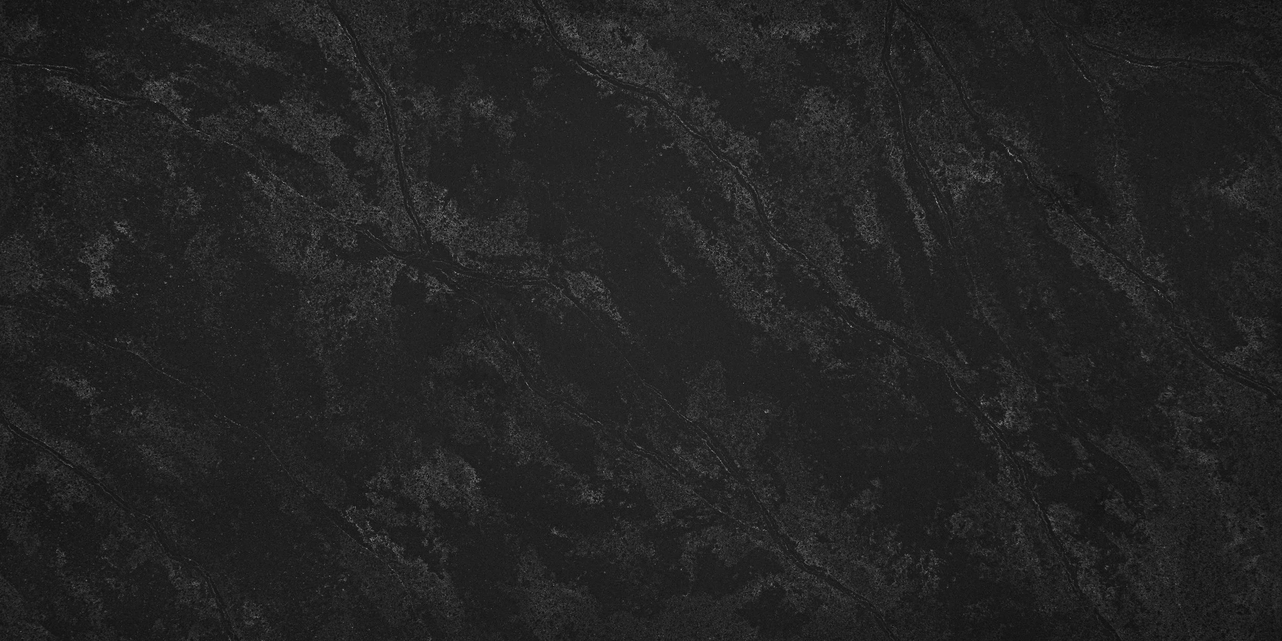 Dark marble or granite surface with subtle veining and texture.
