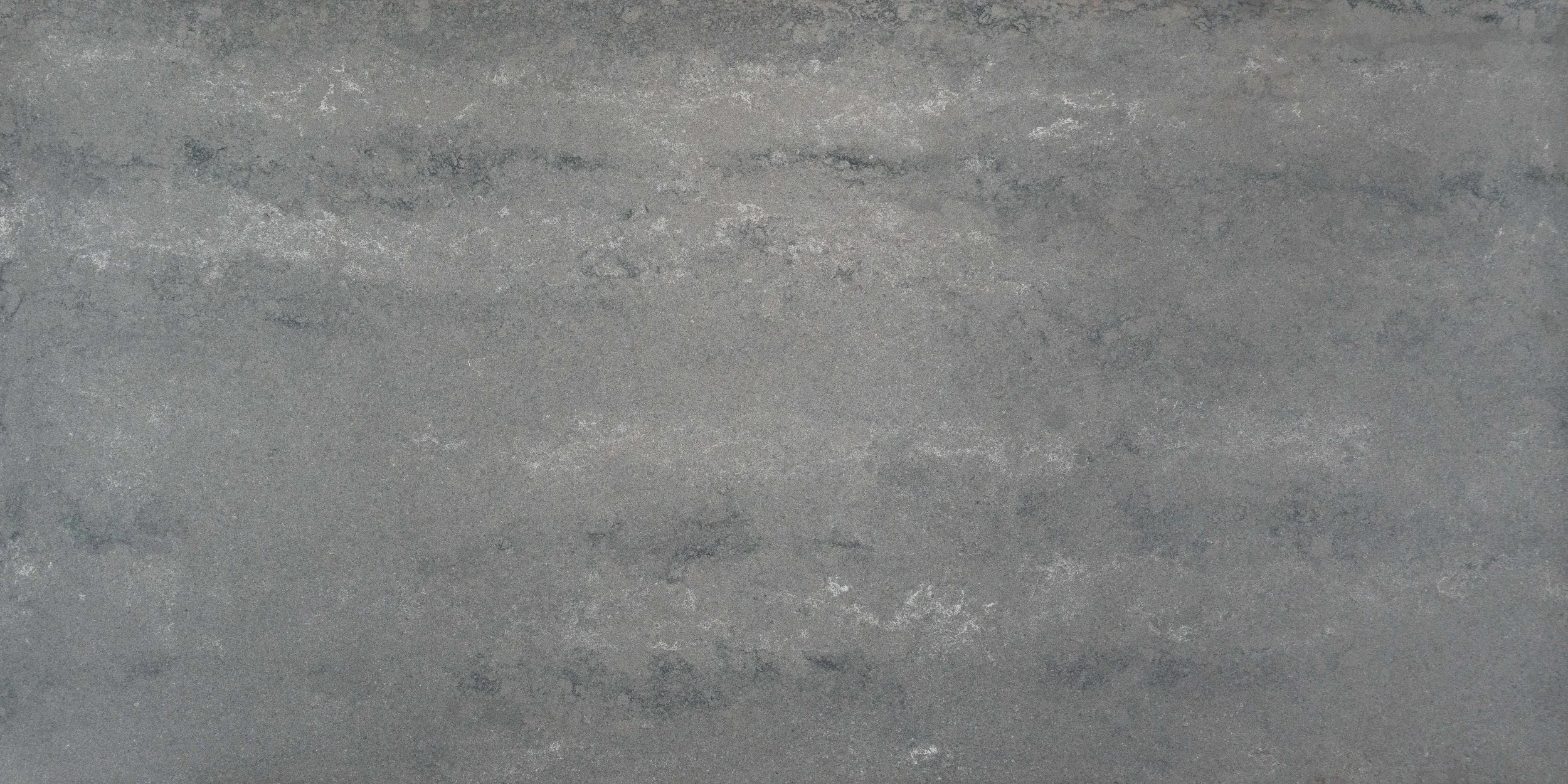 A close-up of a textured gray stone surface with subtle variations in color and pattern.