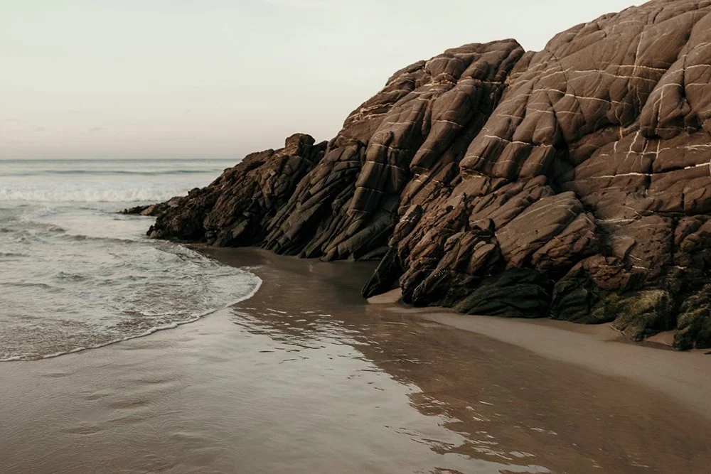 landscape image of a rock bordering the ocean at Pambula Beach
