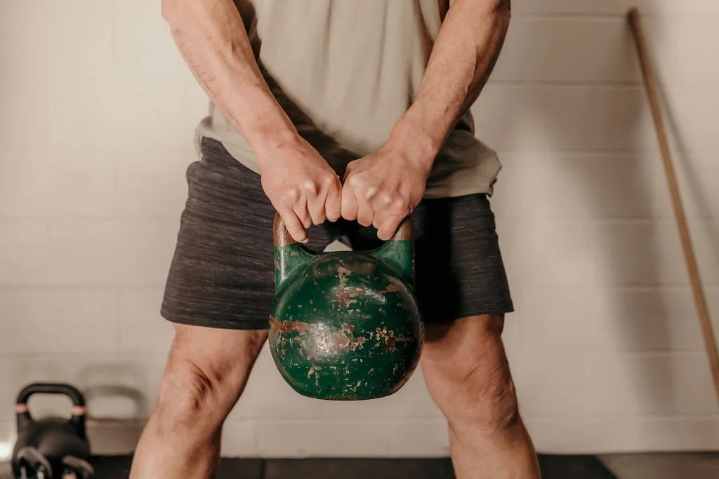 Person lifting a green kettlebell at 4b Gym Pambula NSW.