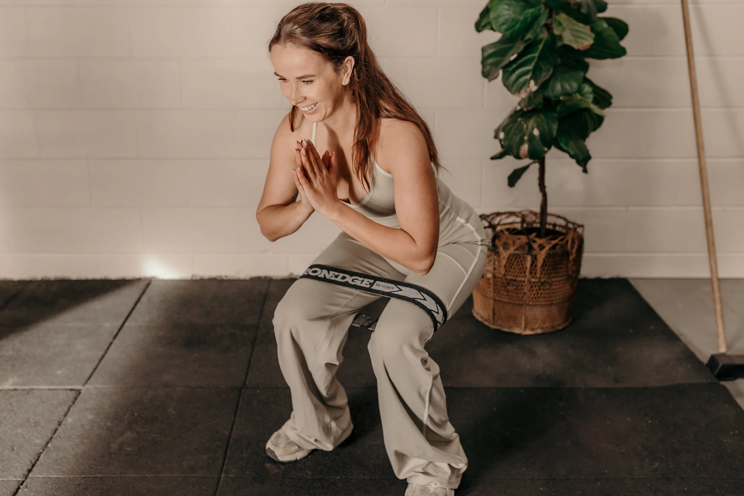 Happy woman doing a squat with band around her legs