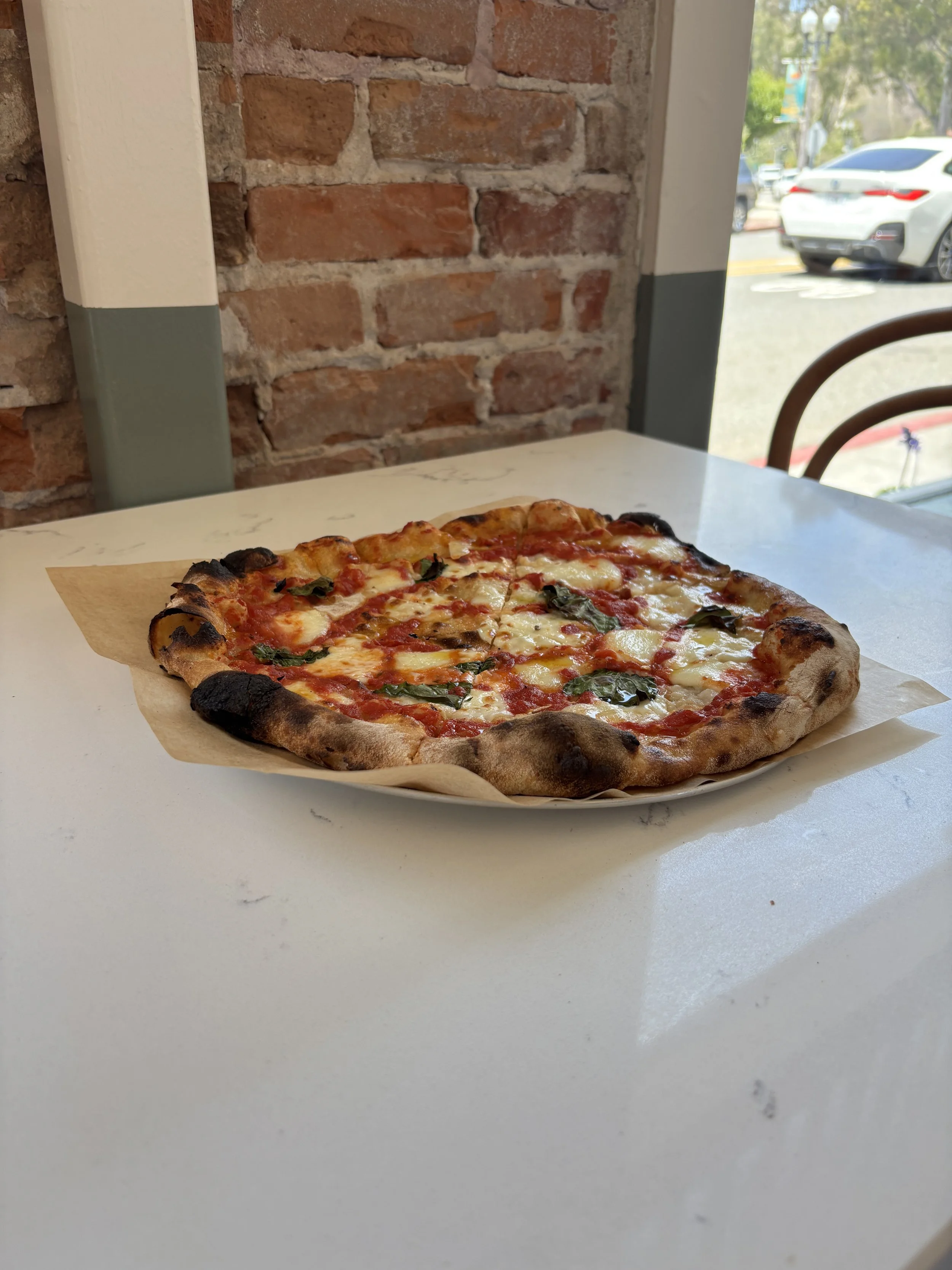 Margherita Pizza on a white table at Mor Mor's Table in Laguna Beach