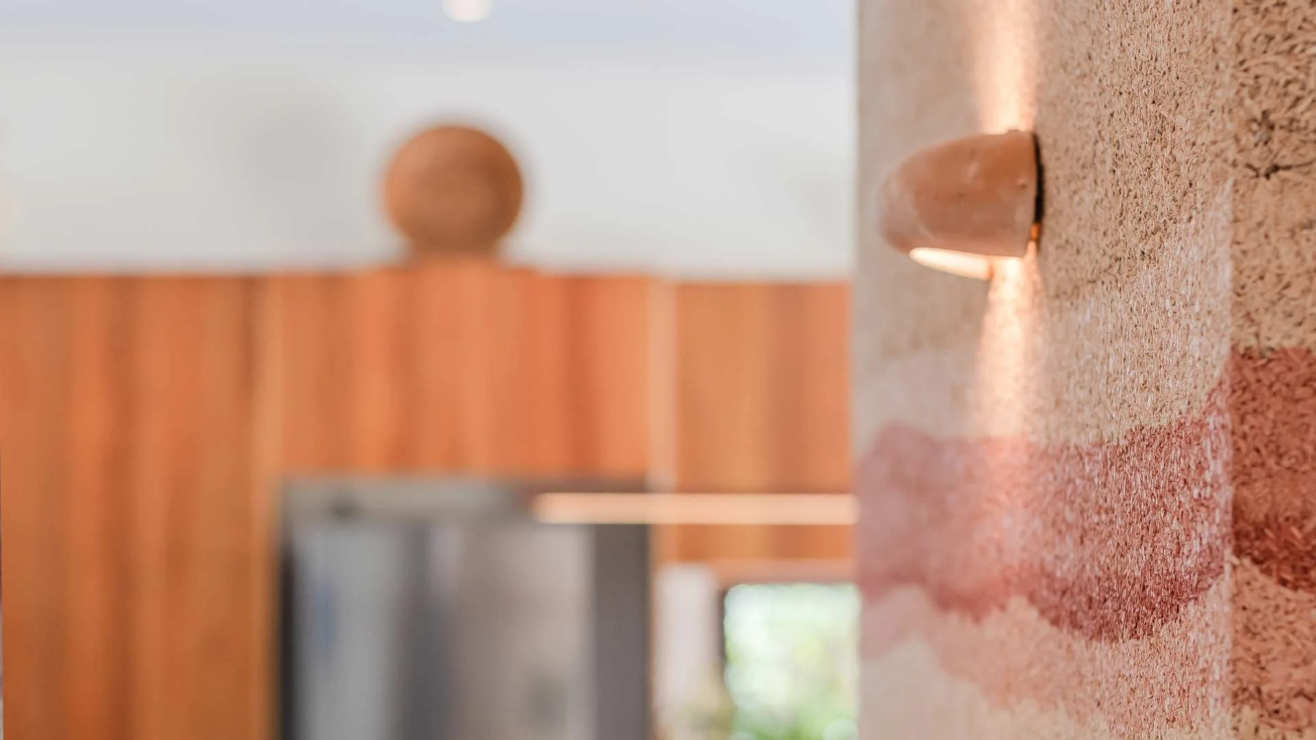 Close-up of a red brick wall with a small, rounded light fixture attached, casting light downward.