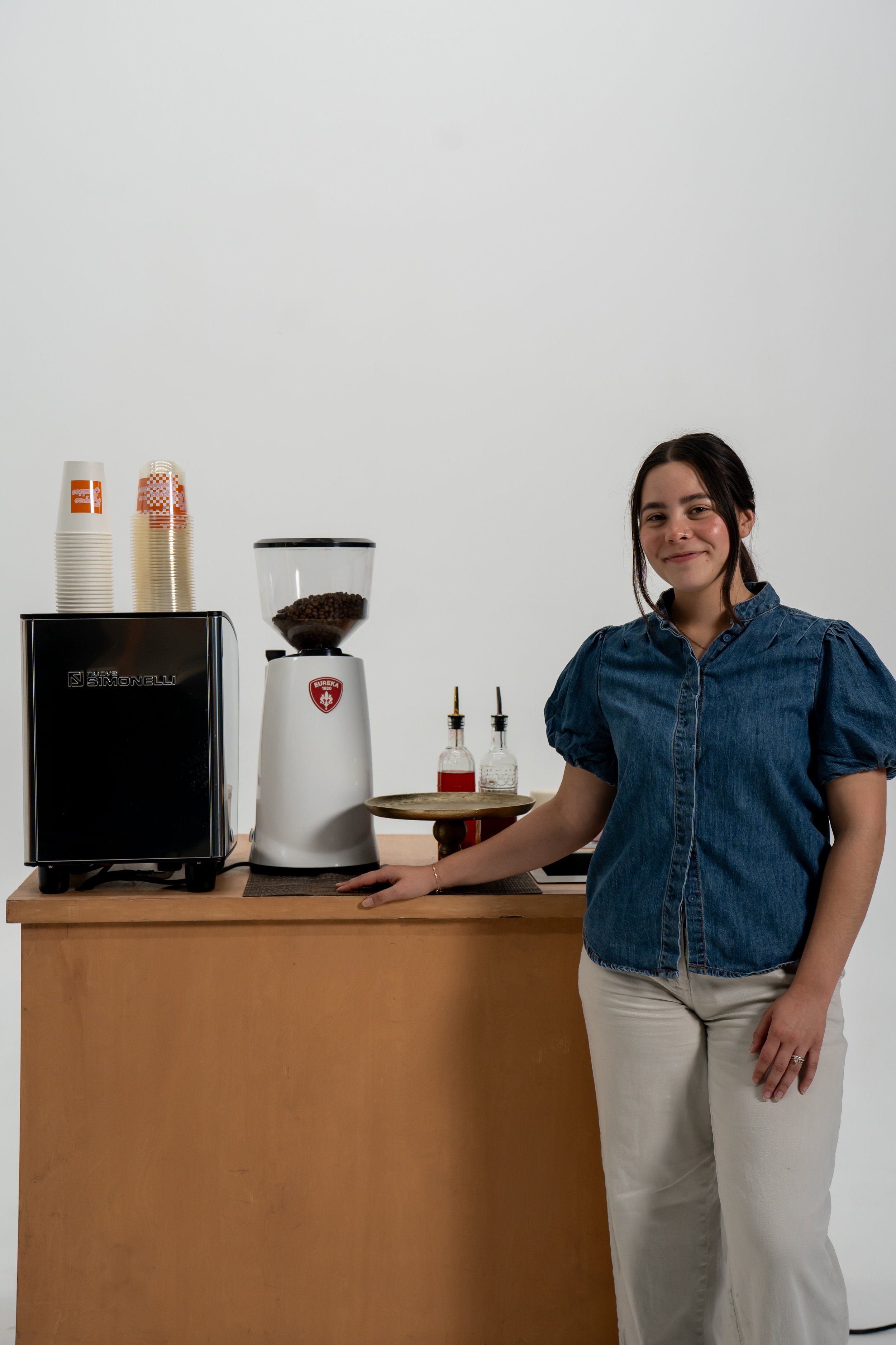 woman in blue denim shirt and white linen pants standing in front of an espresso bar, california, pomona, brea, los angeles, downtown los angeles, long beach, placentia, lake forest, santa margarita, westminster