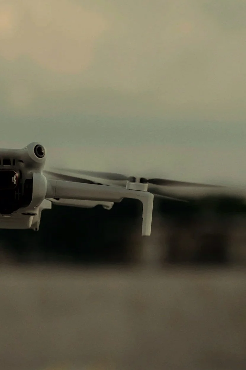 Close-up of a drone with visible propellers in flight against a blurred sky background.