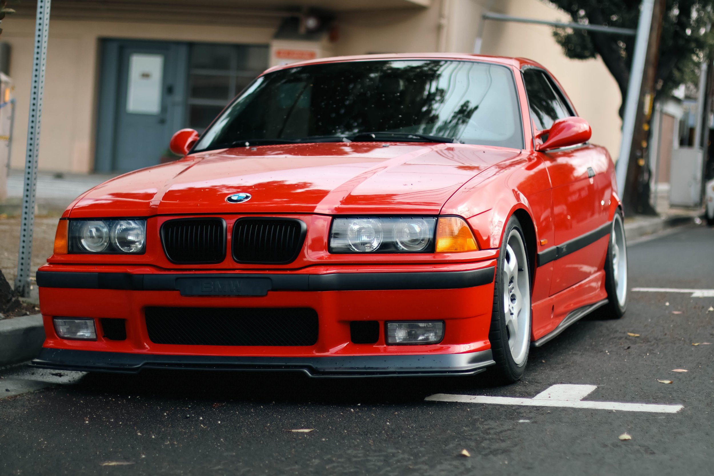 A red BMW car parked on a city street.