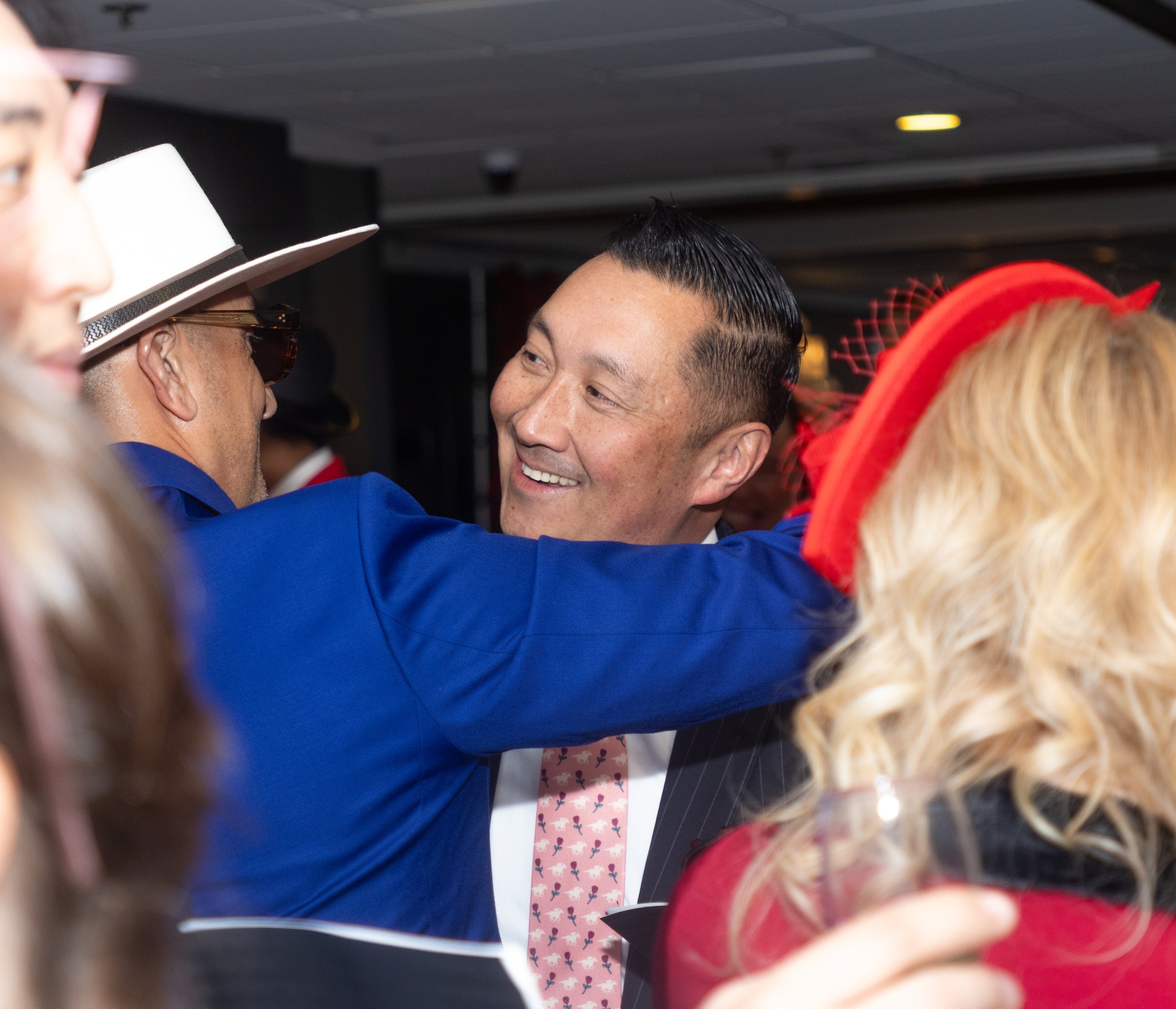 People with celebratory hats and attire in a close-knit gathering, smiling and enjoying each other's company indoors.
