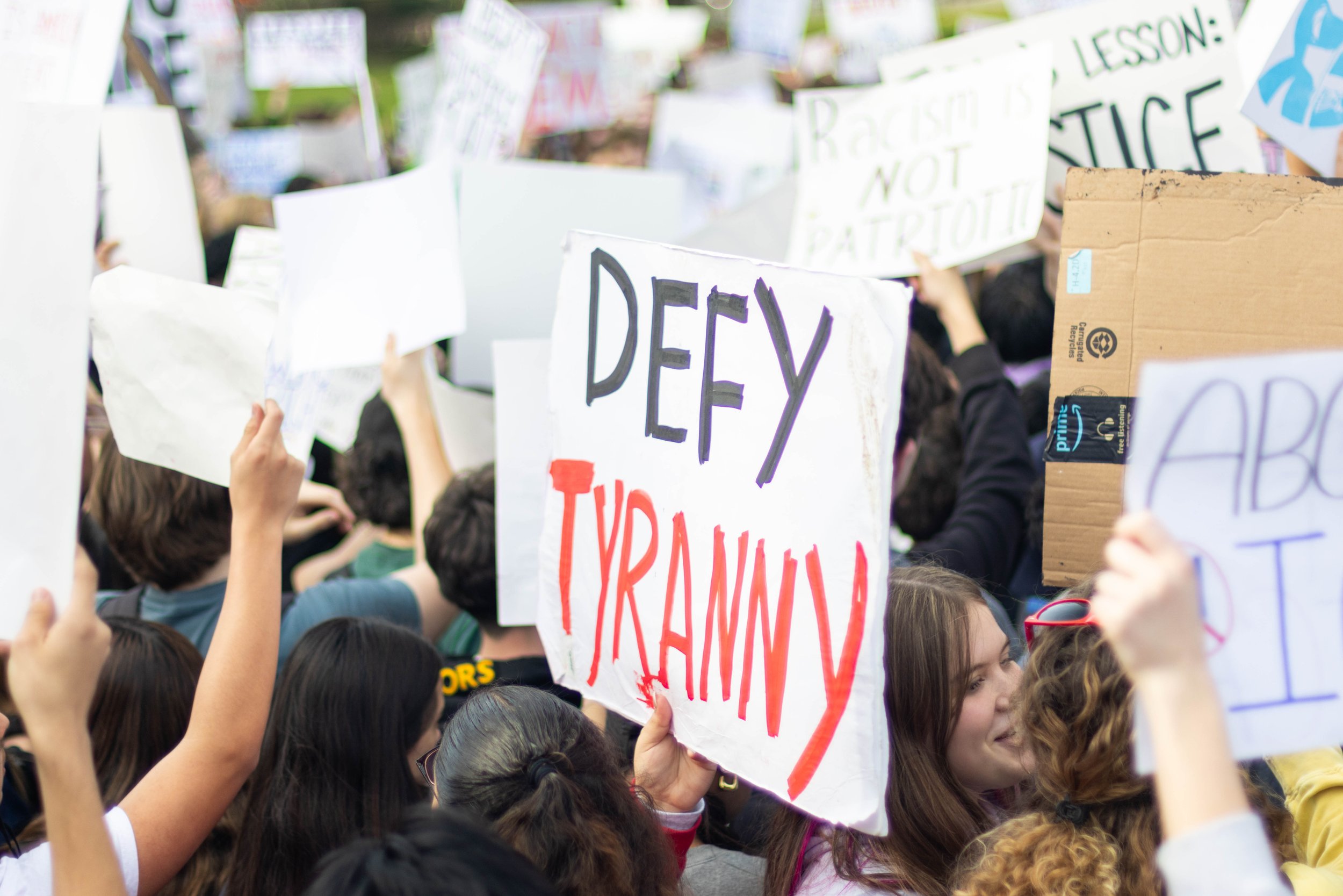 San Mateo High School's Anti-Ice walkout protest with a protest sign saying defy tyranny