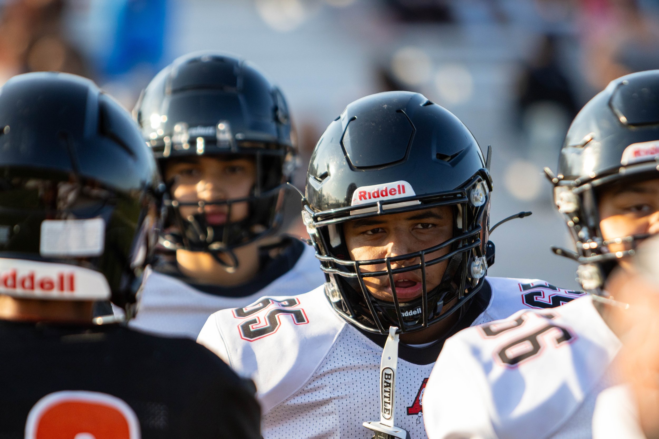 A group of football players wearing black helmets and white jerseys on the field.