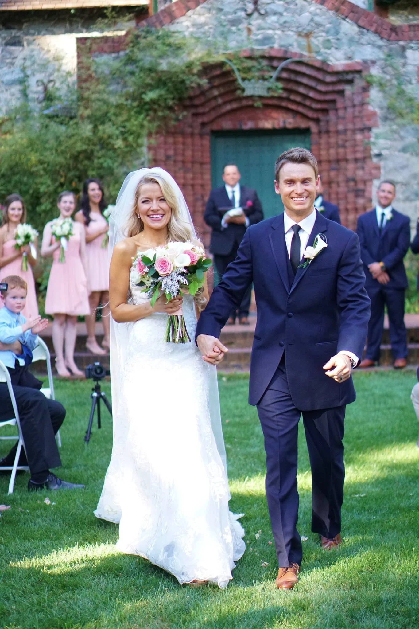 Laurie’s customers, Mariana and Carmen holding hands on a green lawn on their wedding day.