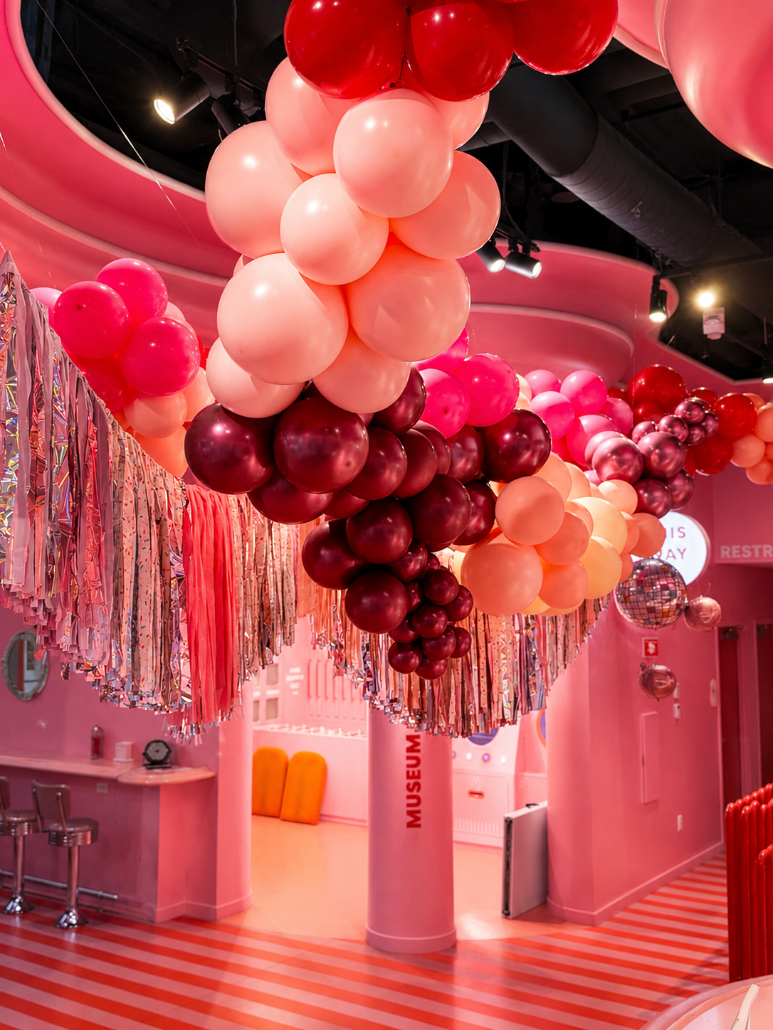 Corporate event balloon ceiling installation with pink and red decor at Museum of Ice Cream Boston.