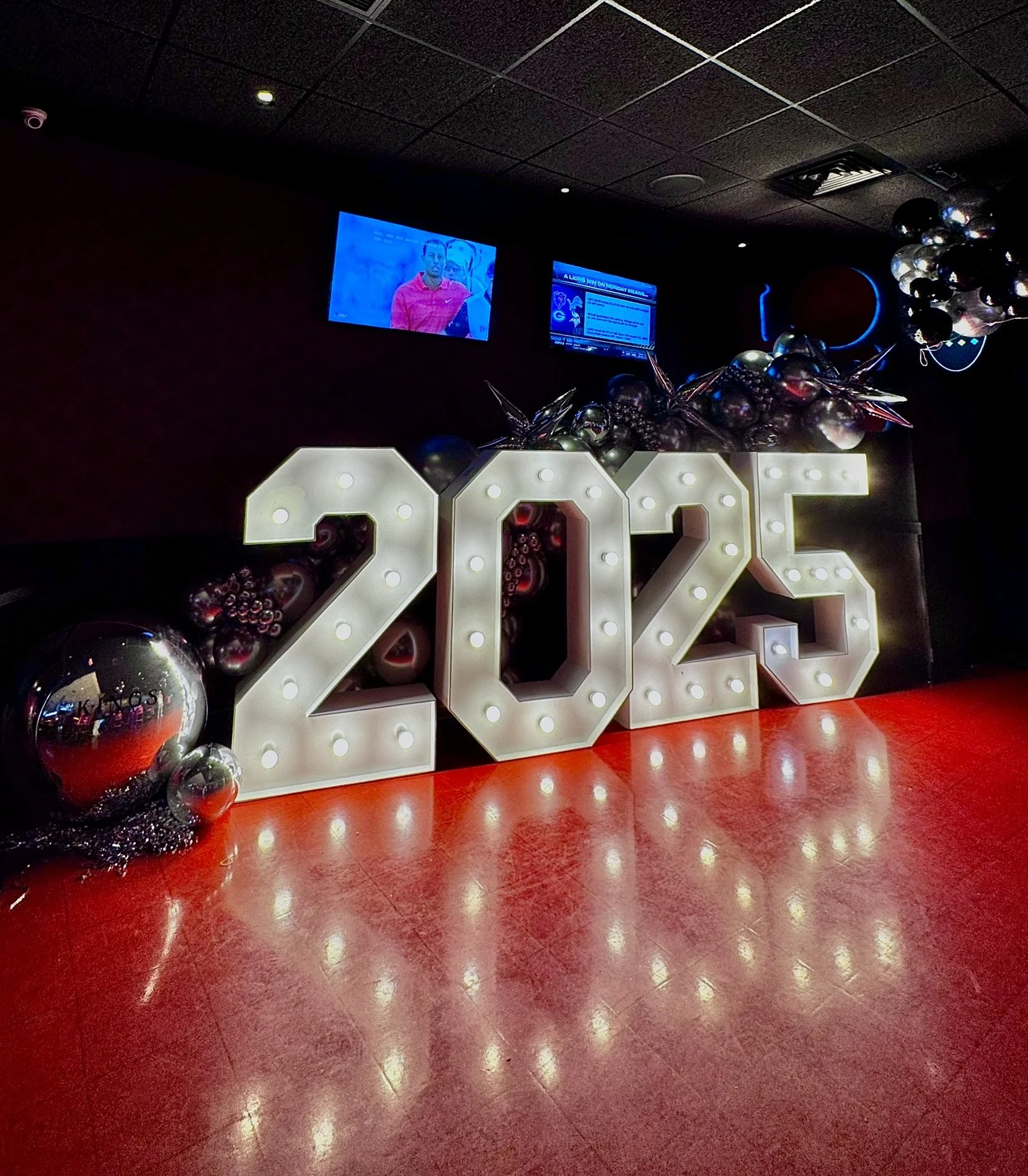 New Year 2025 corporate event decor with illuminated number display and silver balloon styling in kings bowling seaport Boston.
